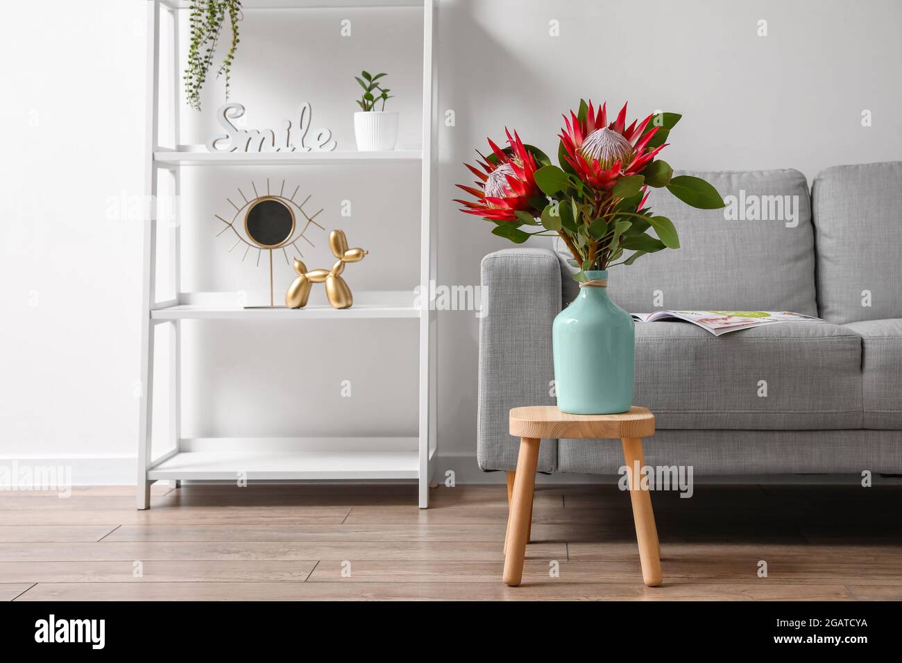Table with protea flowers and sofa in interior of room Stock Photo - Alamy
