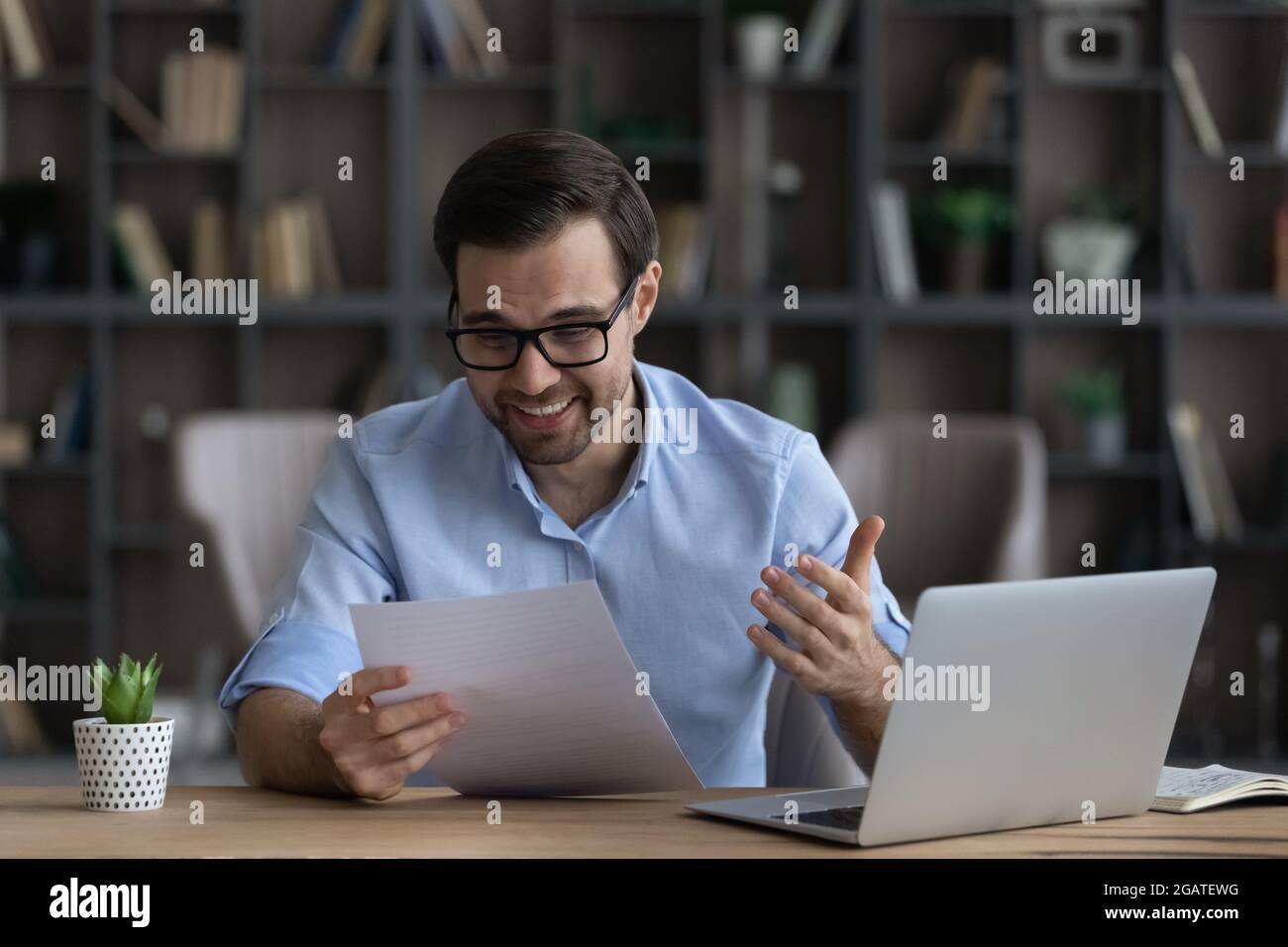 Laughing young man editor reading printed draft of funny article Stock Photo