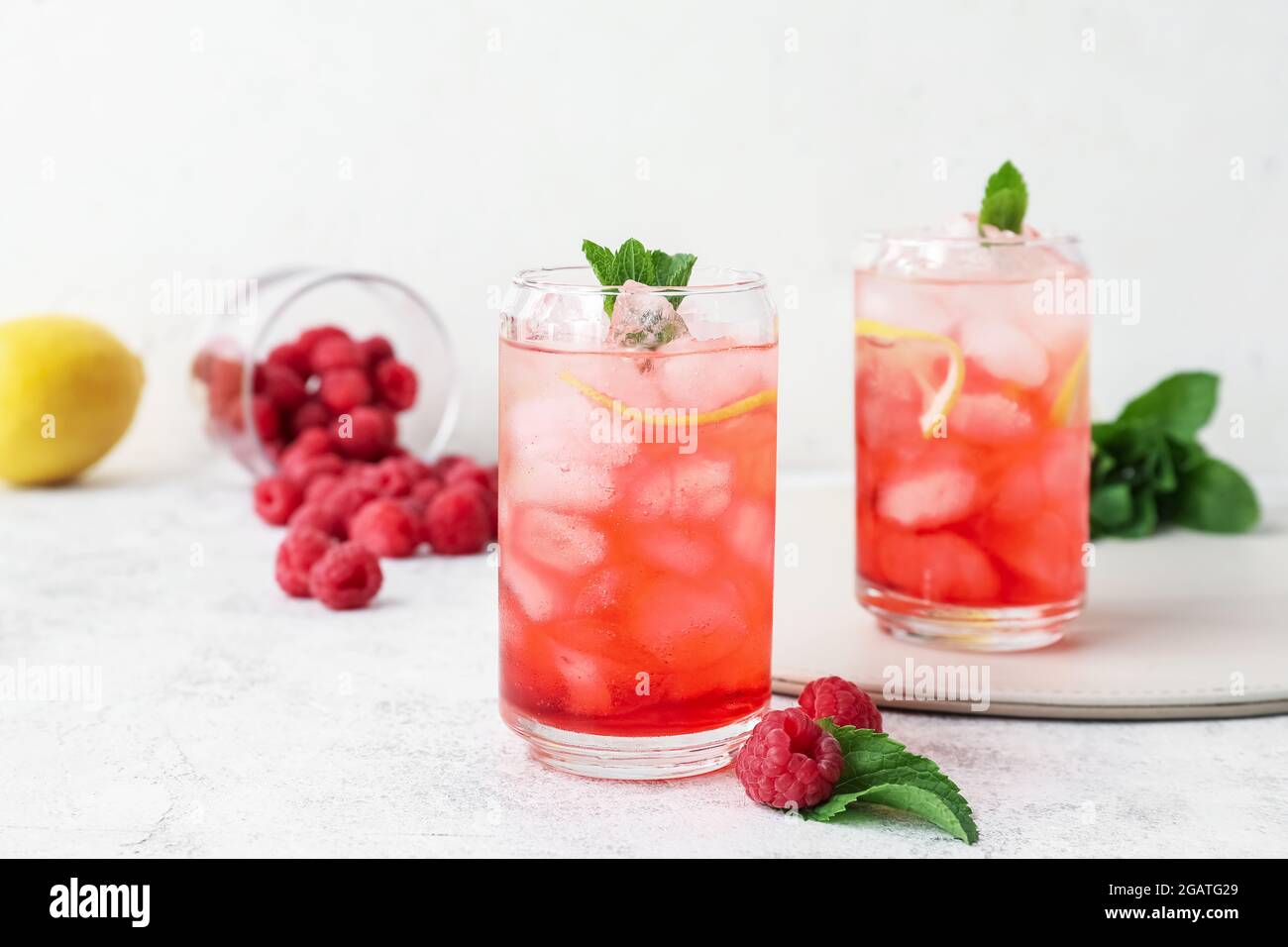 Glasses with tasty raspberry lemonade on light background Stock Photo ...