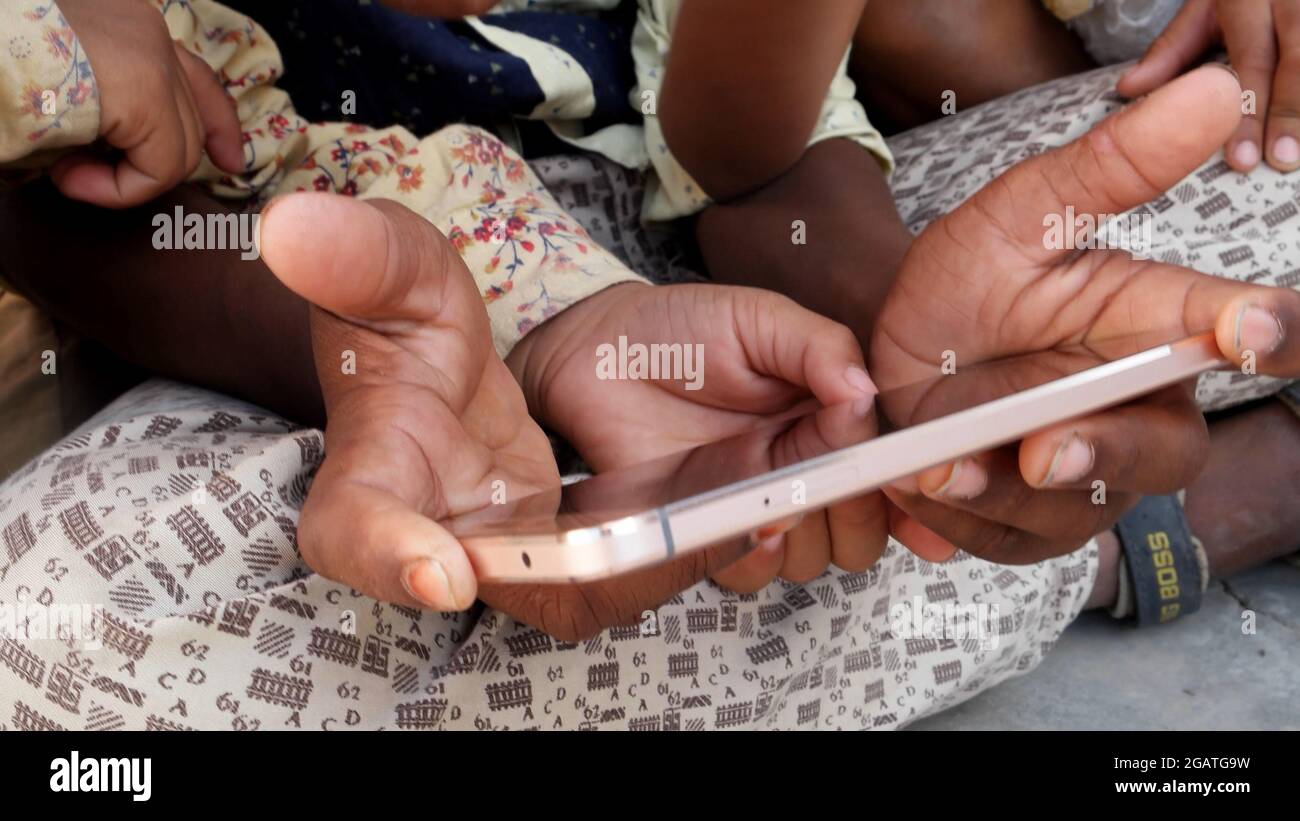 A closeup shot of hands of children playing with a smartphone Stock Photo