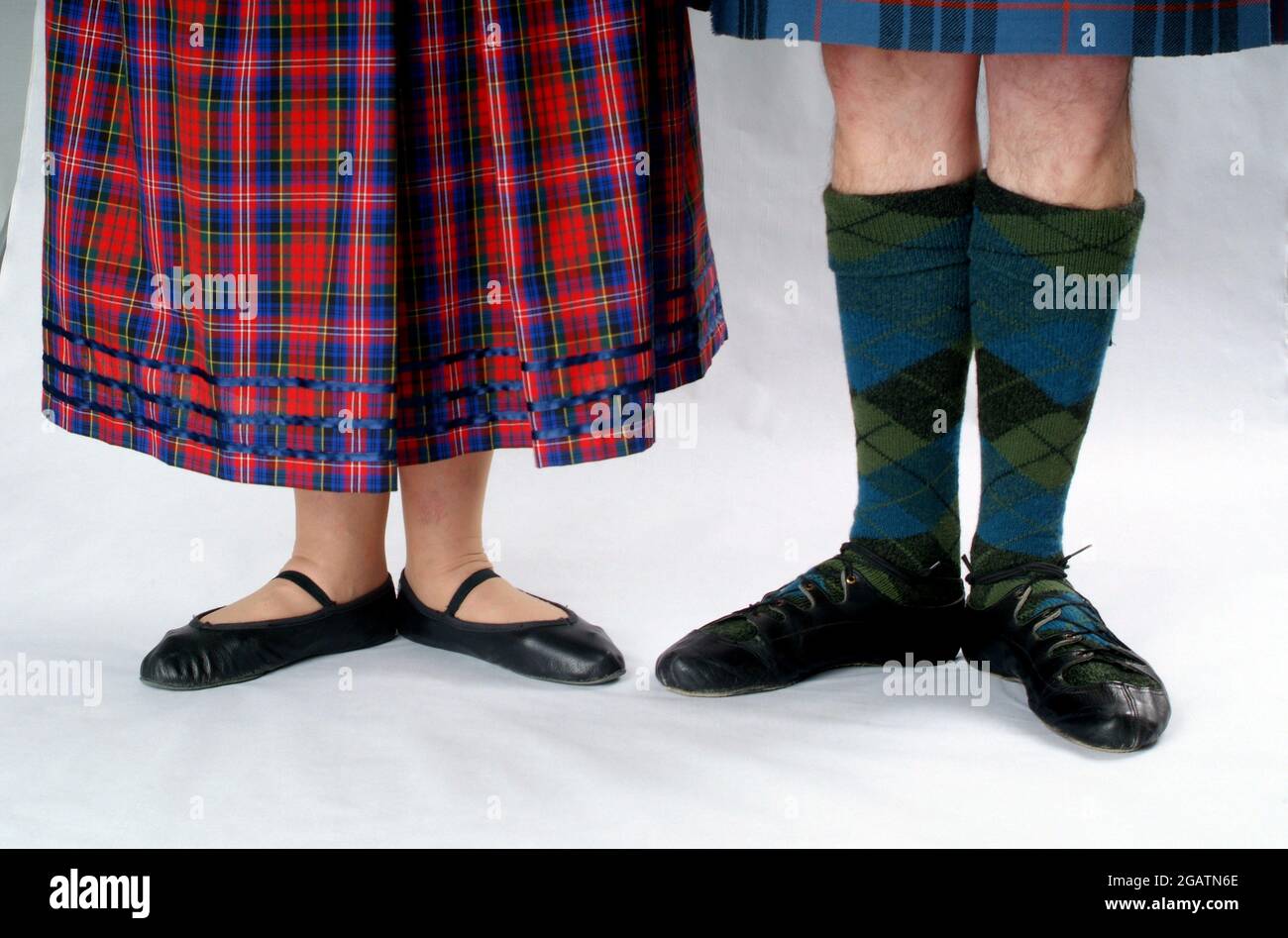 Man and woman couple in Scottish Country Dancing clothes. She wears a tartan skirt, he wears tartan stockings. Both wear shoes known as ghillies Stock Photo