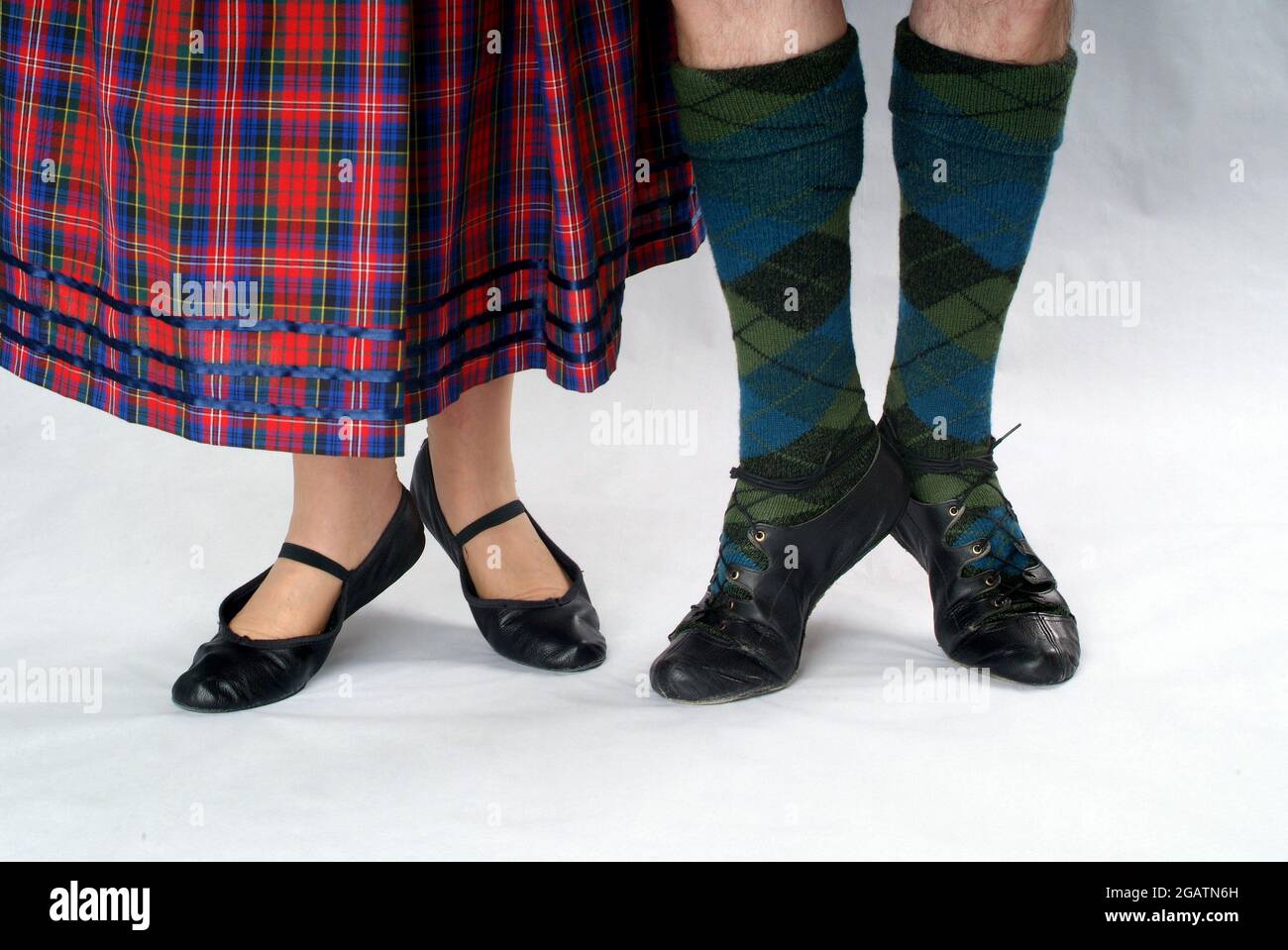 Man and woman couple in Scottish Country Dancing clothes. She wears a tartan skirt, he wears tartan stockings. Both wear shoes known as ghillies Stock Photo
