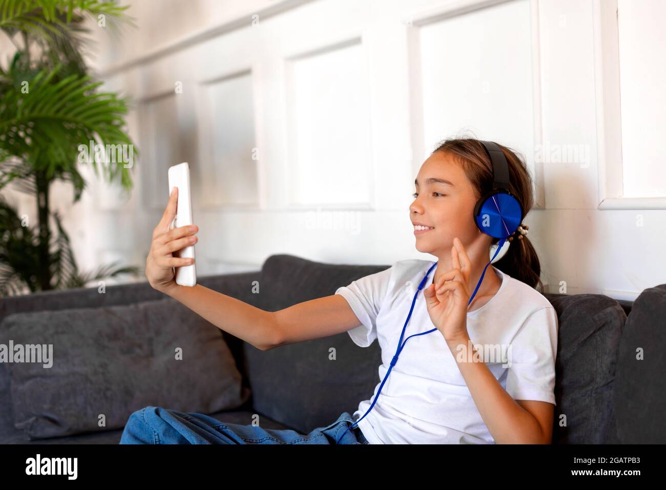 Teenager girl in blue headphones during online video call in home ...