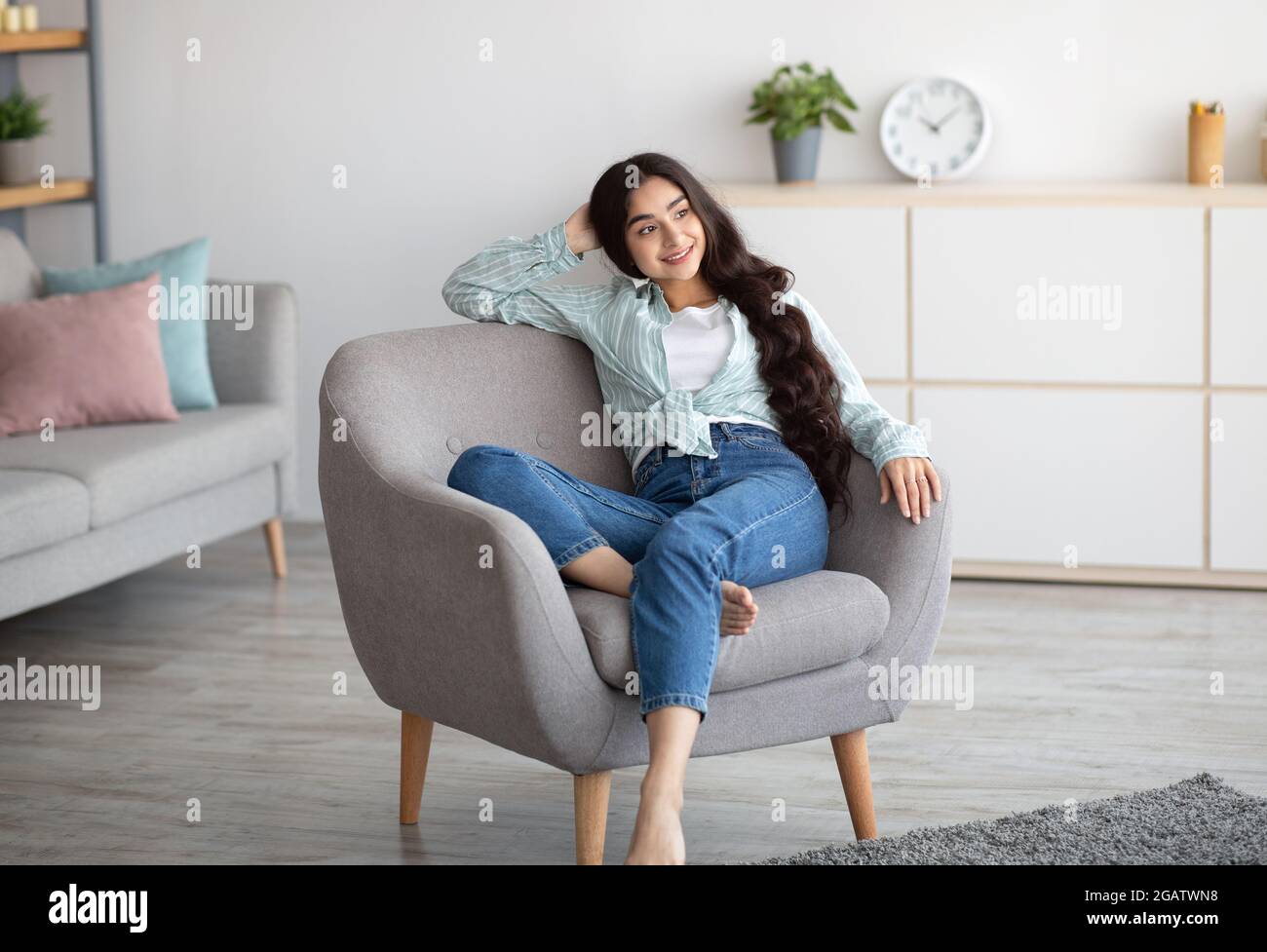 Gorgeous Indian woman sitting in comfy armchair, enjoying lazy morning,  having peaceful weekend at home. Attractive young lady chilling on her day  off Stock Photo - Alamy