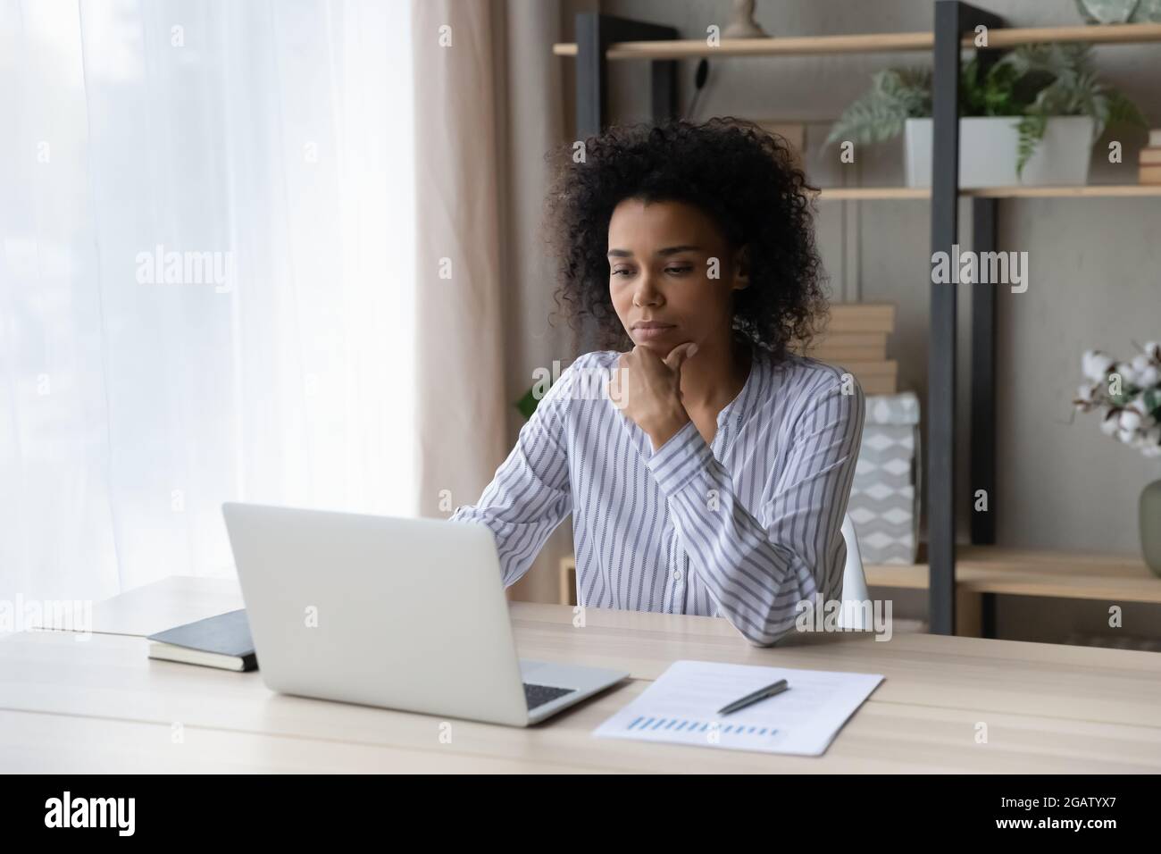 Pensive African American woman work on laptop online Stock Photo - Alamy