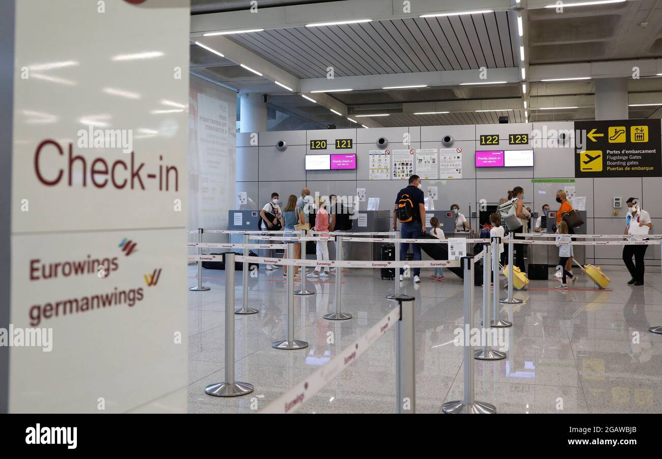 01 August 2021, Spain, Palma: Passengers stand at the Eurowings check-in  counter in the departure area of Palma de Mallorca airport. From 1 August,  all unvaccinated travellers over the age of 12