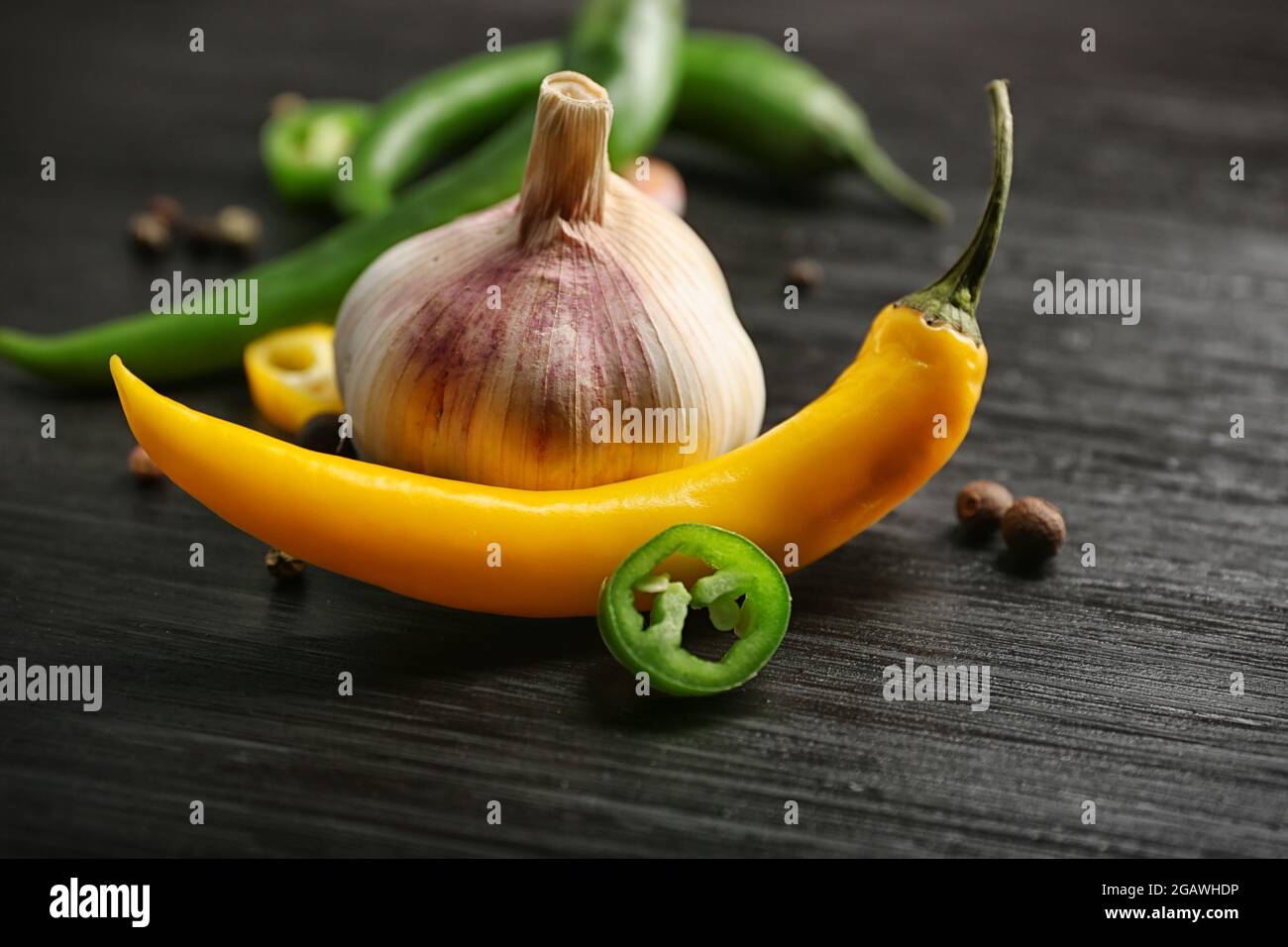 Garlic, green and yellow chili peppers on dark wooden background Stock ...