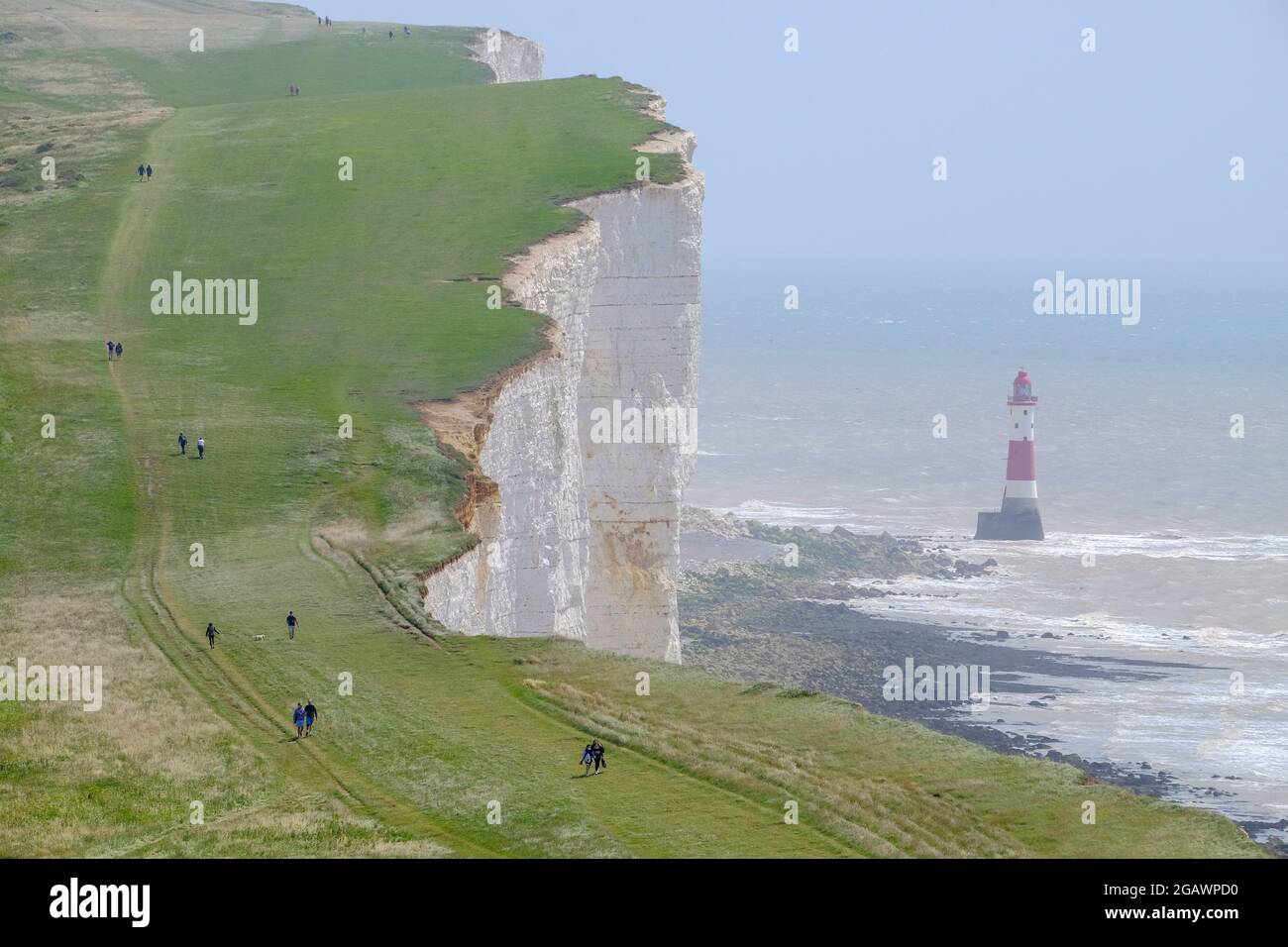 Walkers on the South Downs Way passing the lighthouse at Beachy Head, East Sussex, UK Stock Photo