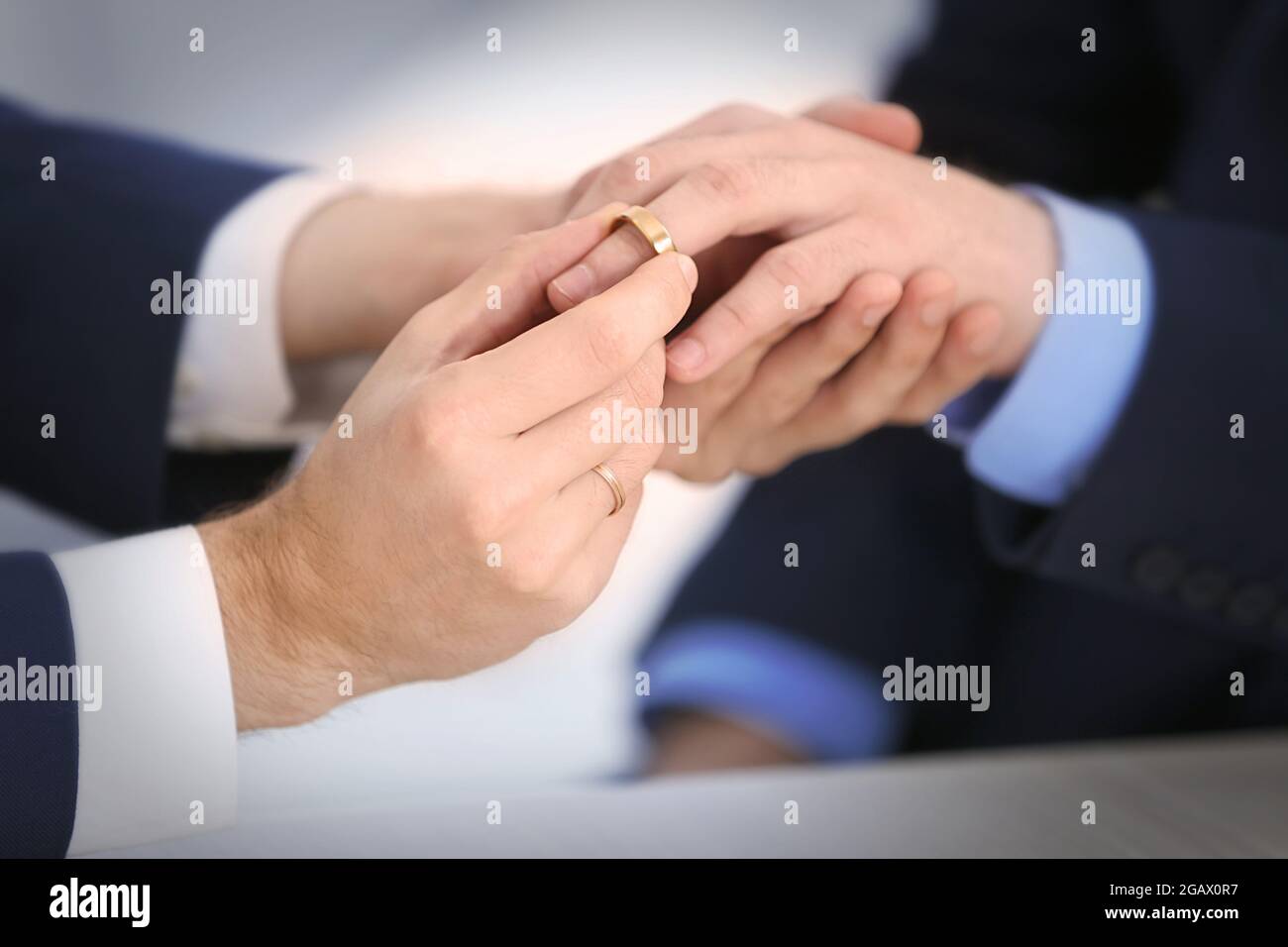 One groom placing the ring on another man's finger Stock Photo