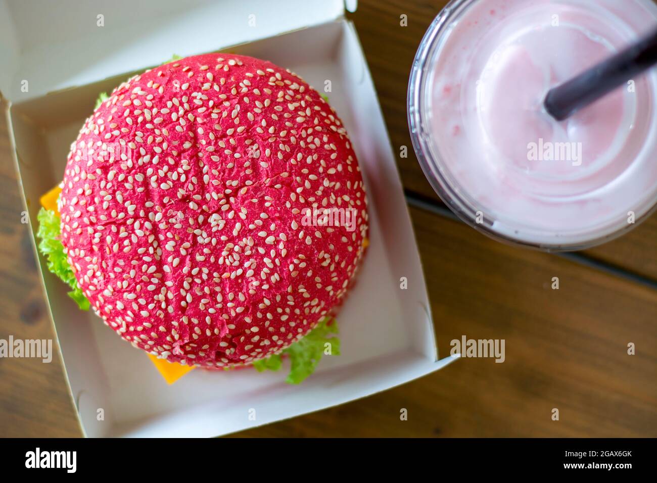 Colored pink beetroot gluten-free hamburger bun with vegetarian burger, with pink milkshake. Healthy alternative burger. Trendy food. Top view. Stock Photo