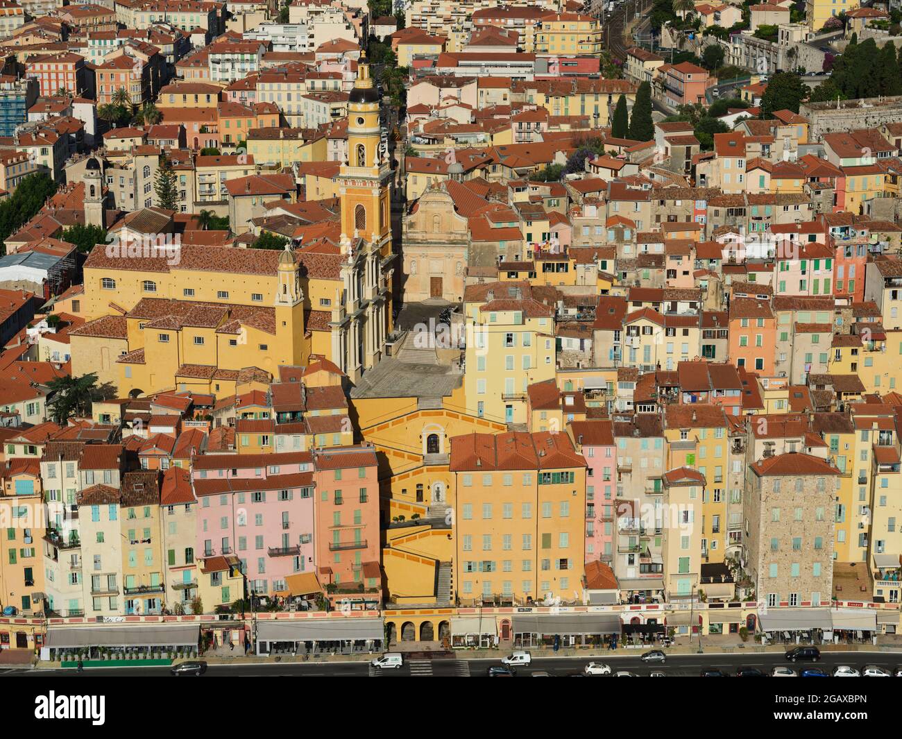 AERIAL VIEW. Basilica surrounded by the colorful medieval homes in the Old Town of Menton. French Riviera, Alpes-Maritimes, France. Stock Photo