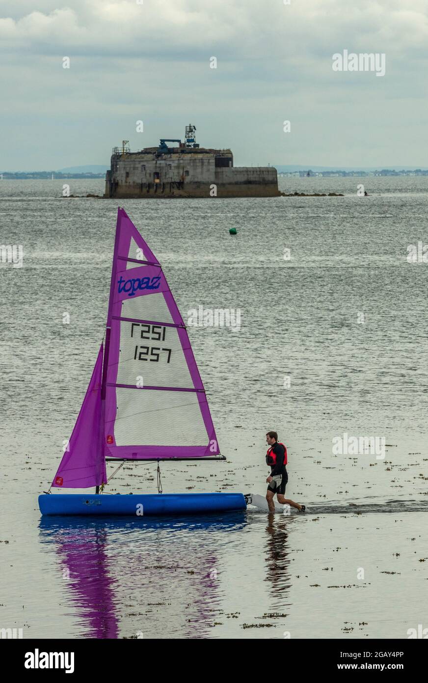 Man beaching a small sailing dinghy at bembridge on the Isle of wight
