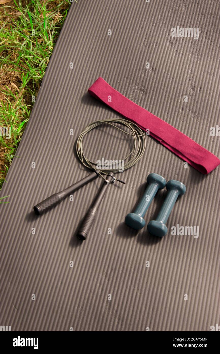 Vertical image workout props (elastic band, weights and rope )needed to do pilates class outdoor. Pilates Outdoor Workout 2021 Stock Photo