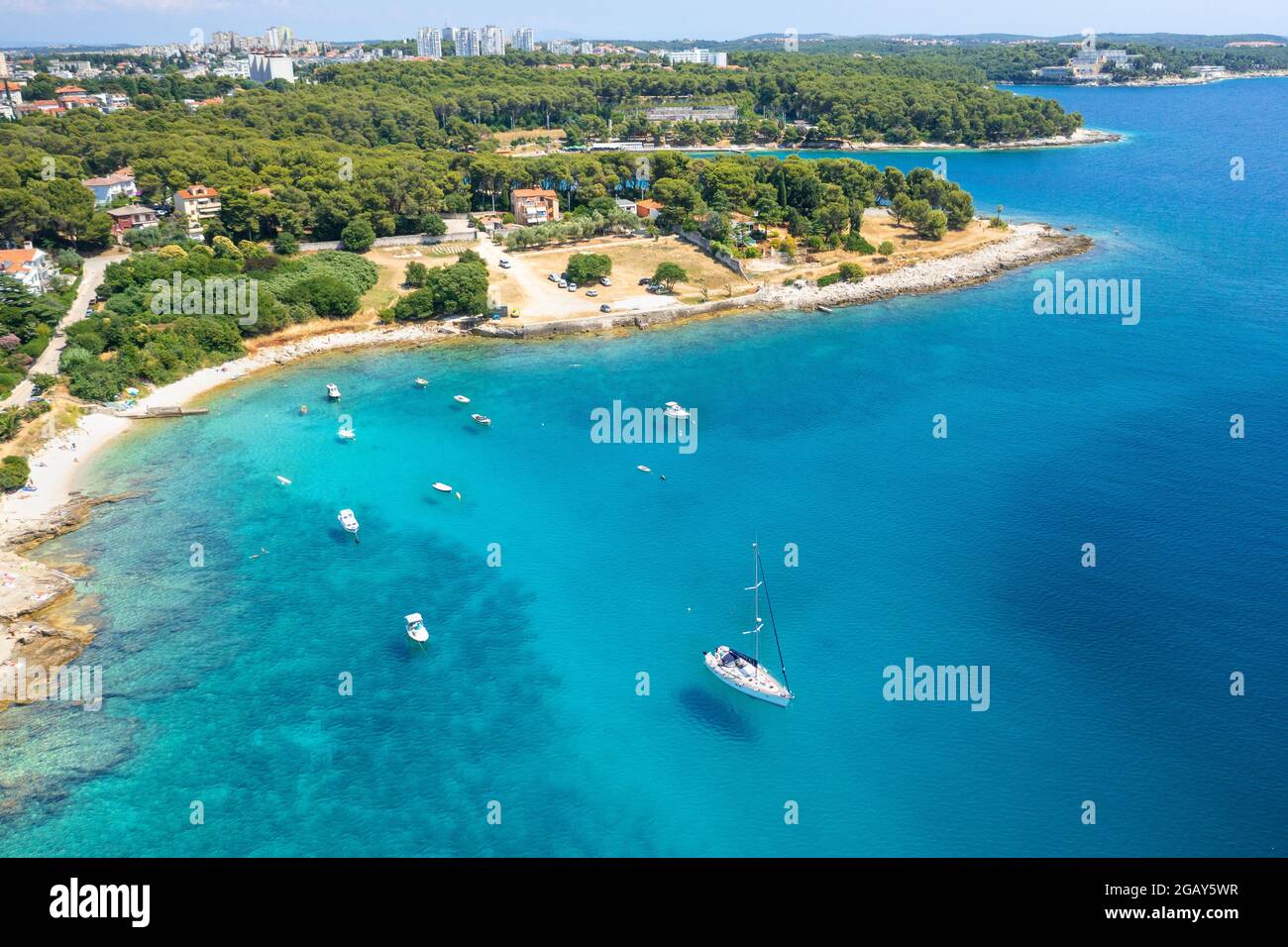 Aerial view of sailboat and small boats or yachts in the turquoise waters of the Adriatic sea close to beach of island. Stock Photo