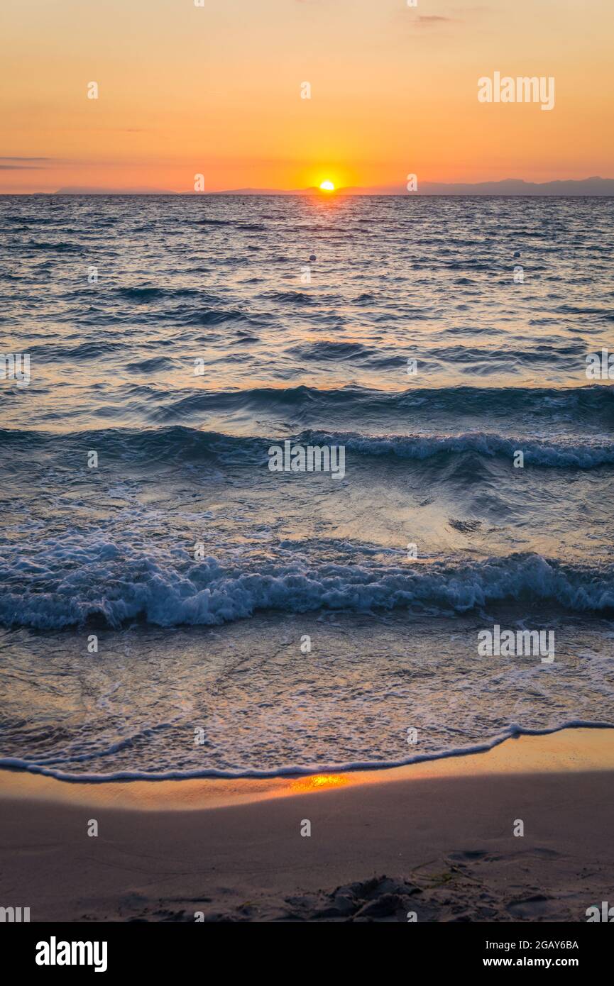 Beautiful sunrise over the sea on the beach of Torre Dell'Orso. Salento coast, Apulia. Italy, Puglia. Bright colorful orange blue sunset over water. No people. Stock Photo