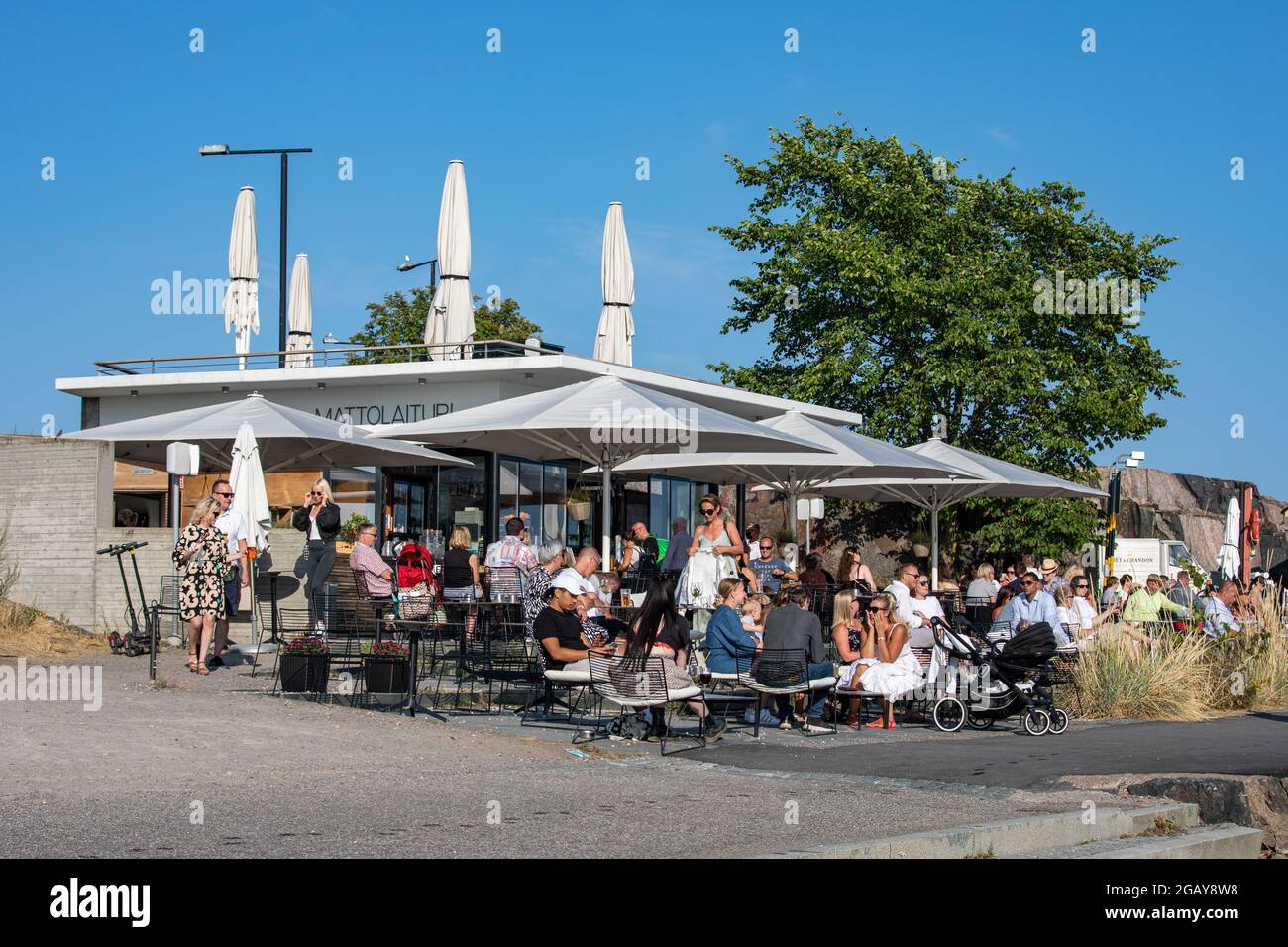 People enjoying beverages and warm summer evening at Mattolaituri outdoor café in Kaivopuisto district of Helsinki, Finland Stock Photo