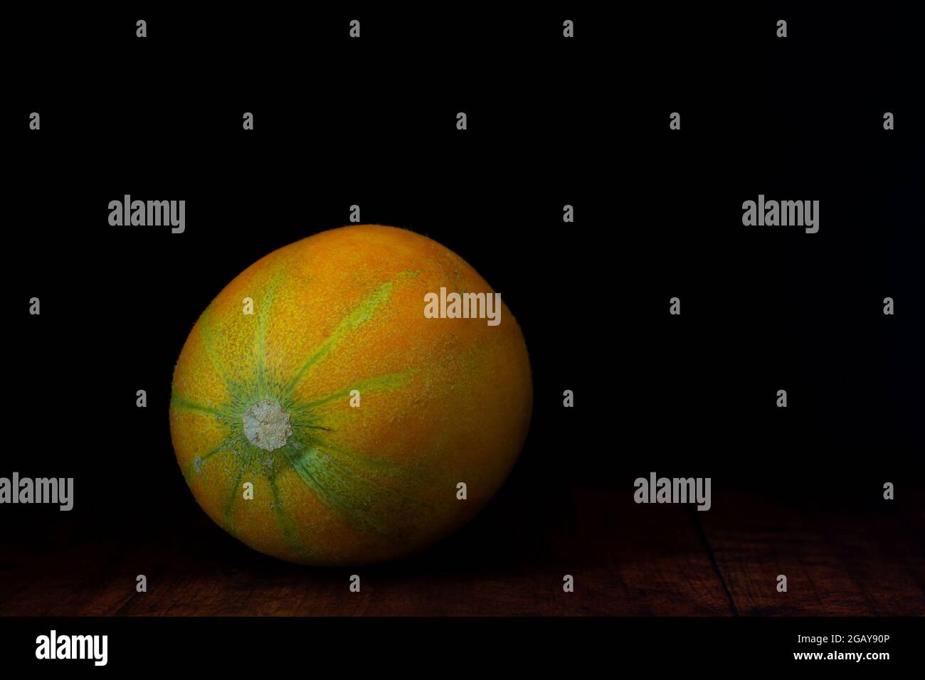 Muskmelon (Israel cantaloupe or Ha Ogen variety) is lying on a rustic weathered wood planks background. Stock Photo
