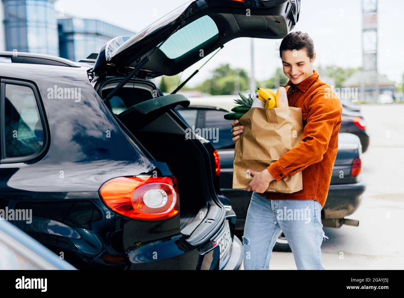 young-man-putting-bags-with-product-in-car-trunk-copy-space-2GAYJ5J.jpg