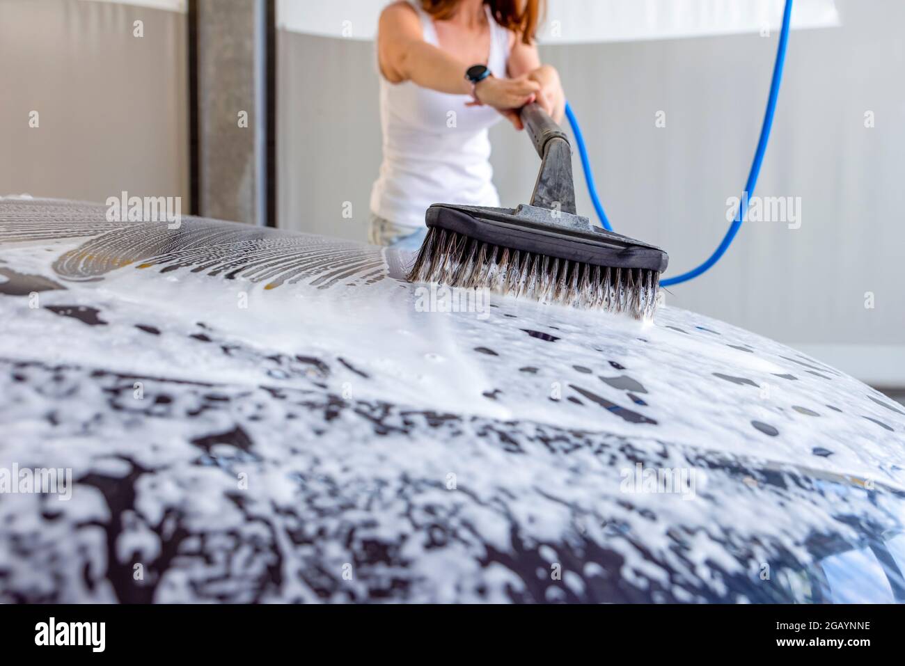 The woman washes the car. A woman at a car wash washes her car with a
