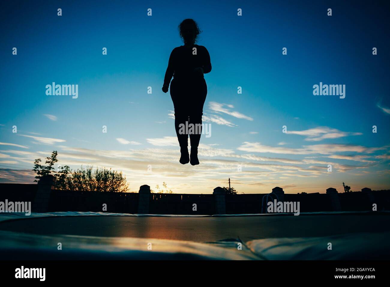 Silhouette Of Beautiful Plus Size Young Woman Girl Jumping On Trampoline Stock Photo