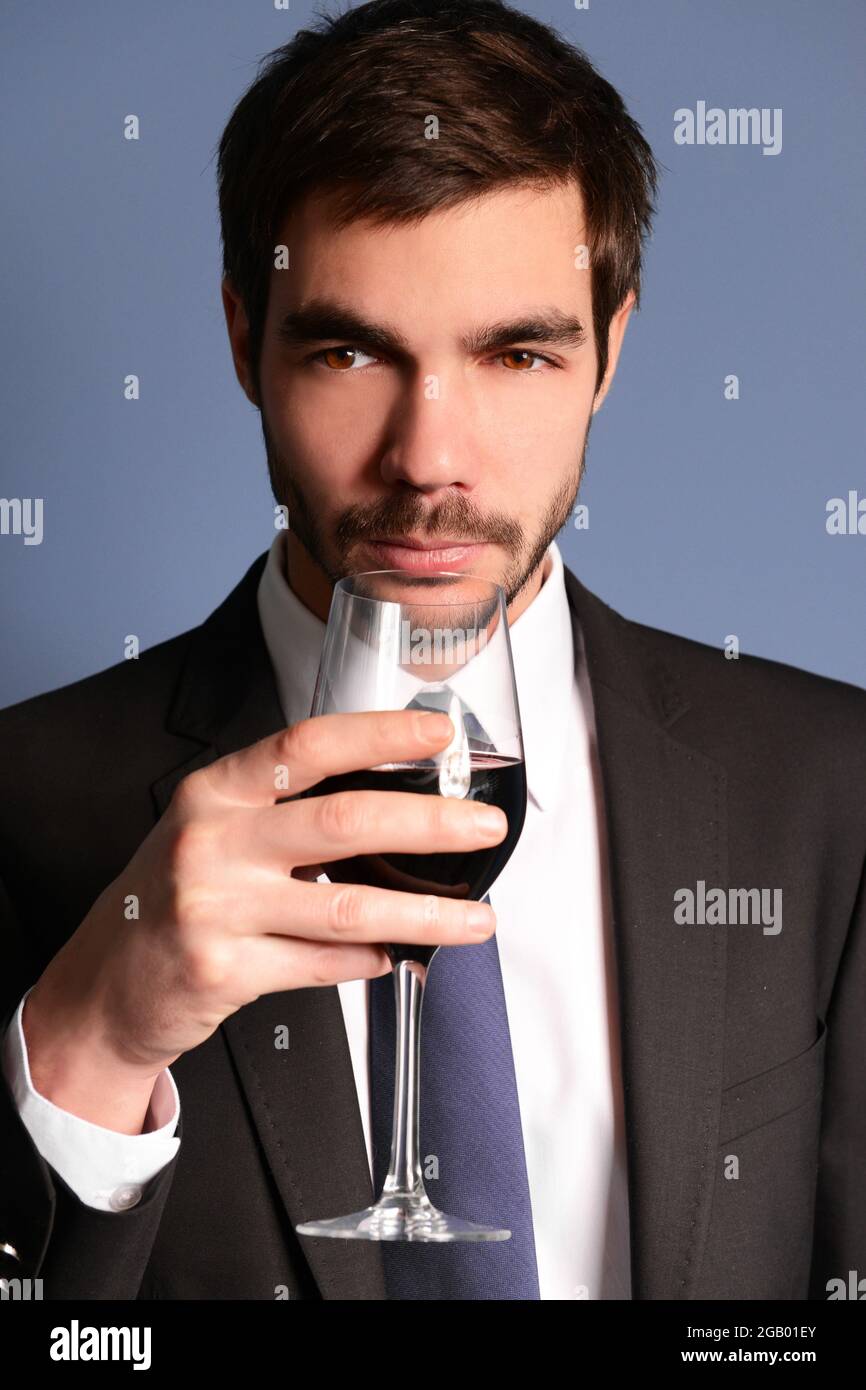 Man sniffing red wine in glass on blue background Stock Photo - Alamy
