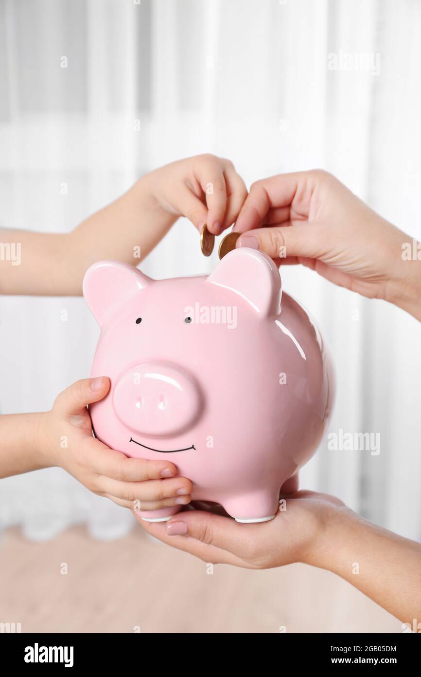 Savings concept. Hand putting coin in the piggy bank Stock Photo - Alamy