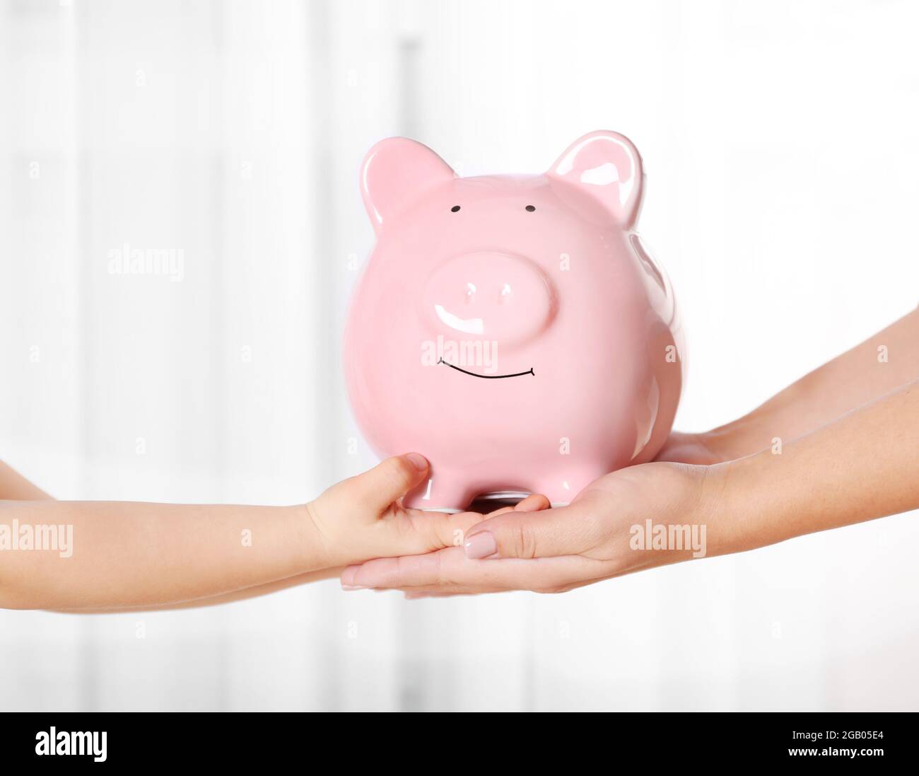 Savings concept. Piggy bank in parent and child hands Stock Photo - Alamy