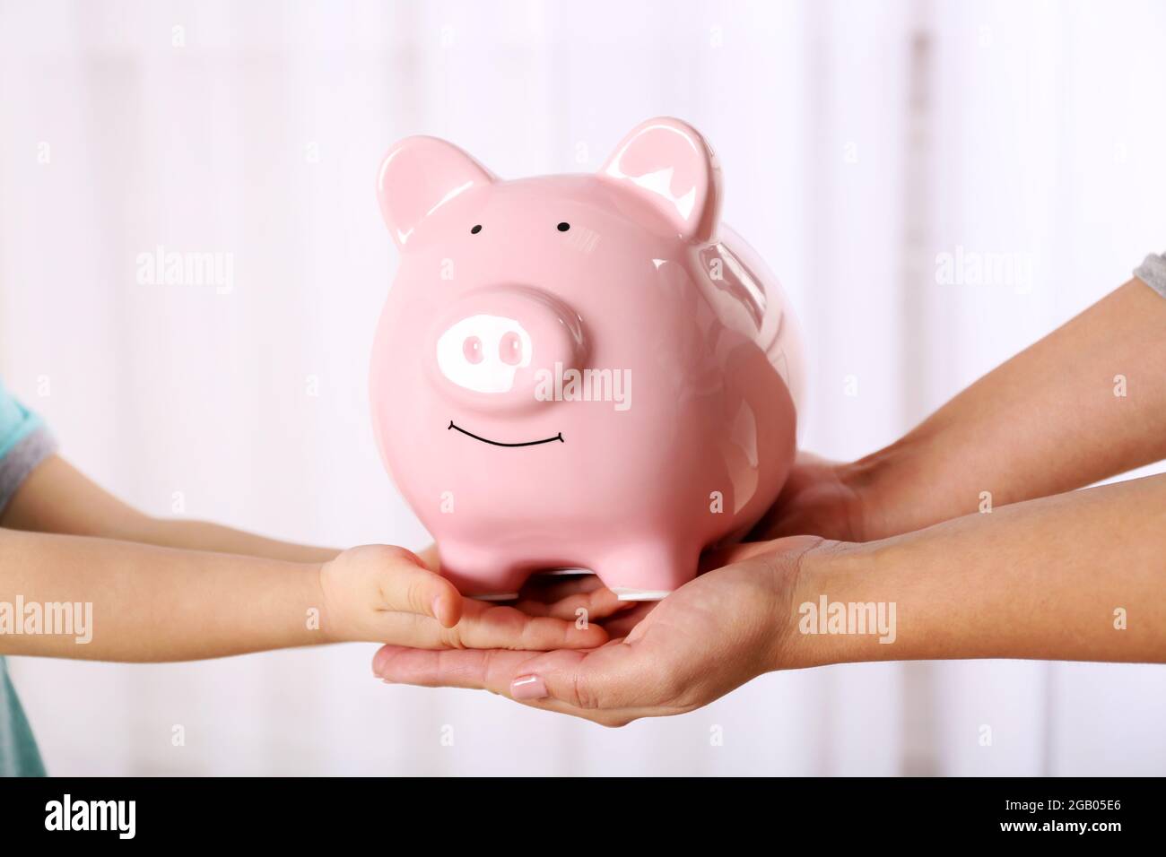 Savings concept. Piggy bank in parent and child hands Stock Photo - Alamy