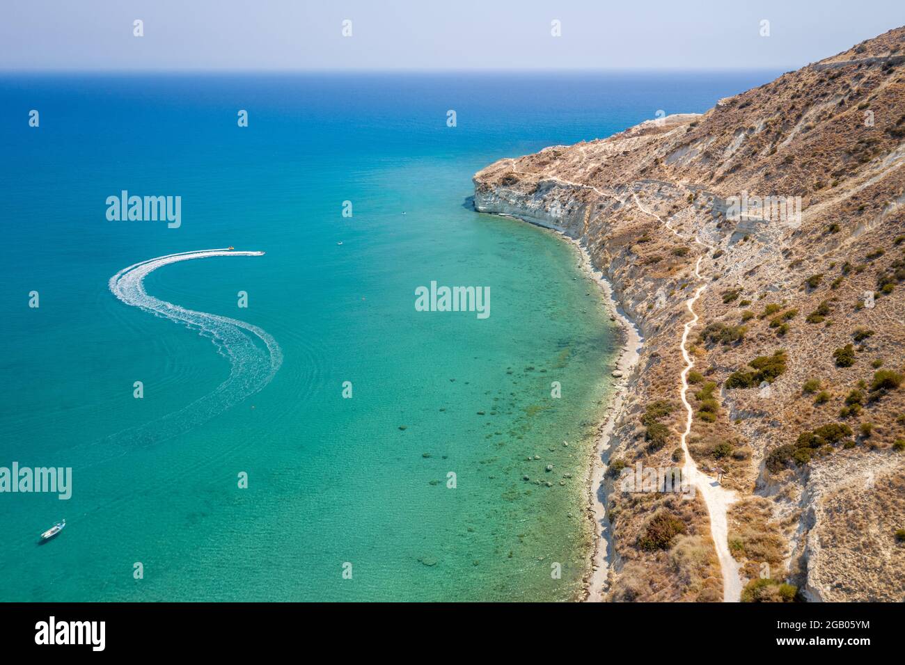 Motor boats leaving trail in Pissouri bay, Cyprus with cliffs shaped like giant turtle and Mediterranean sea on background, aerial seascape Stock Photo