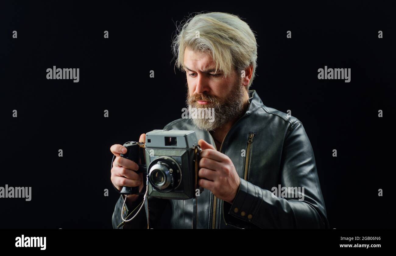 Bearded man with Vintage photo camera. Stylish photographer in leather jacket with Retro camera. Stock Photo