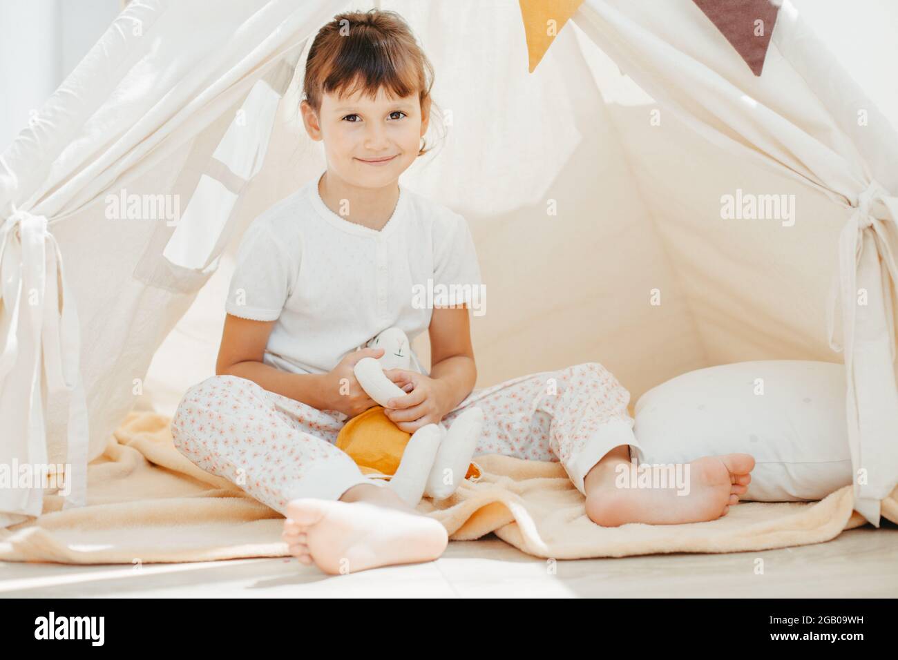 cute girl playing in teepee with fabric tilda bunny at home Stock Photo ...