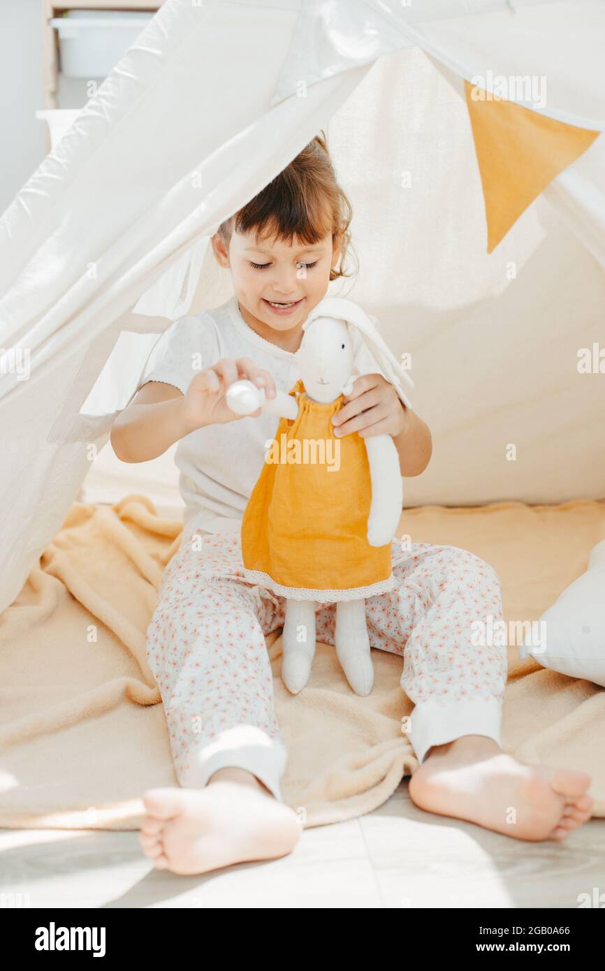 cute girl playing in teepee with fabric tilda bunny at home Stock Photo ...