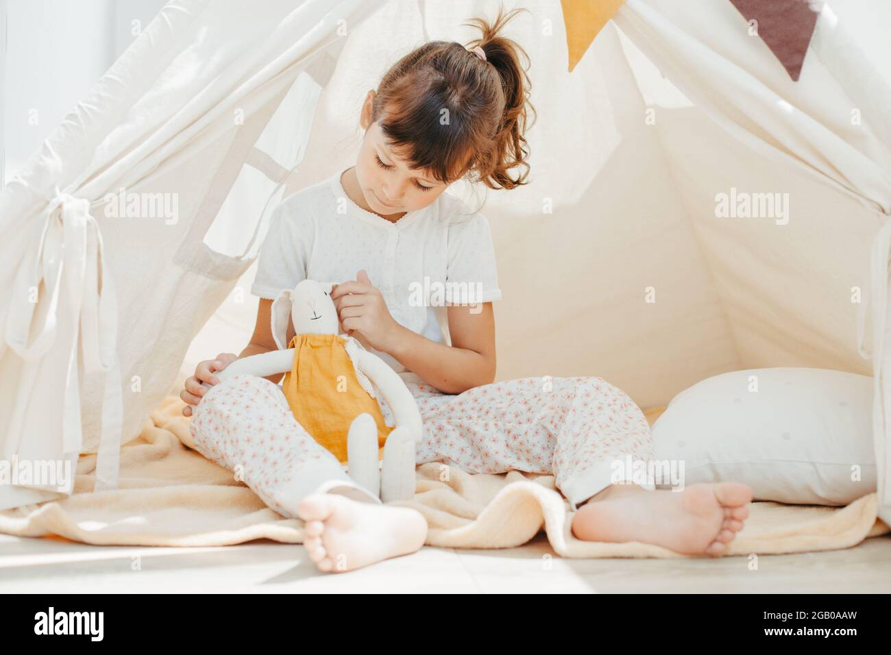 cute girl playing in teepee with fabric tilda bunny at home Stock Photo ...