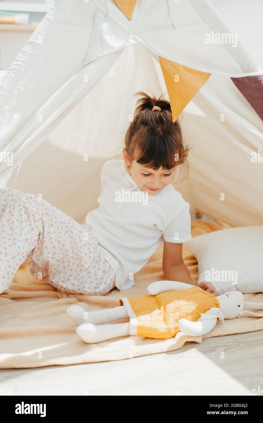 cute girl playing in teepee with fabric tilda bunny at home Stock Photo ...