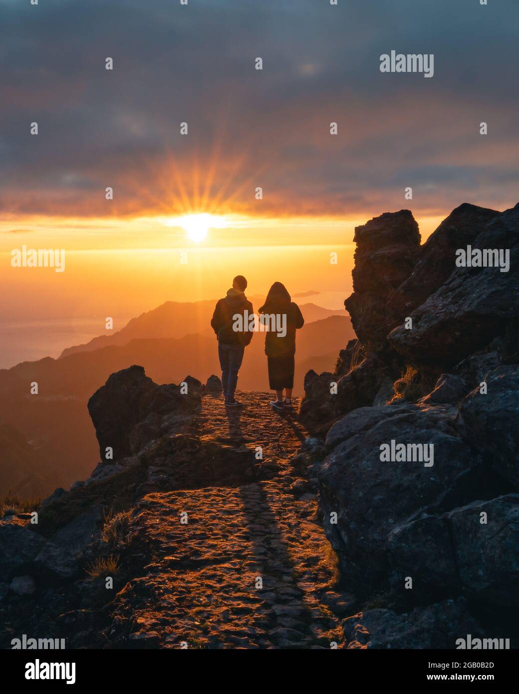 Happy young couple watching sunrise from the peak od Pico do Arieiro in Madeira. Silhouette of couple on the mountains Stock Photo