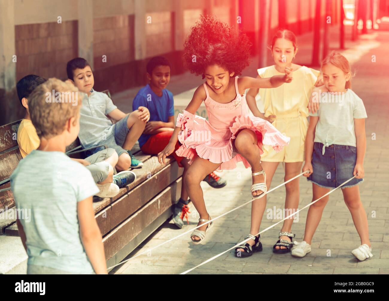 Mexican girl playing rubber band jumping game with european friends