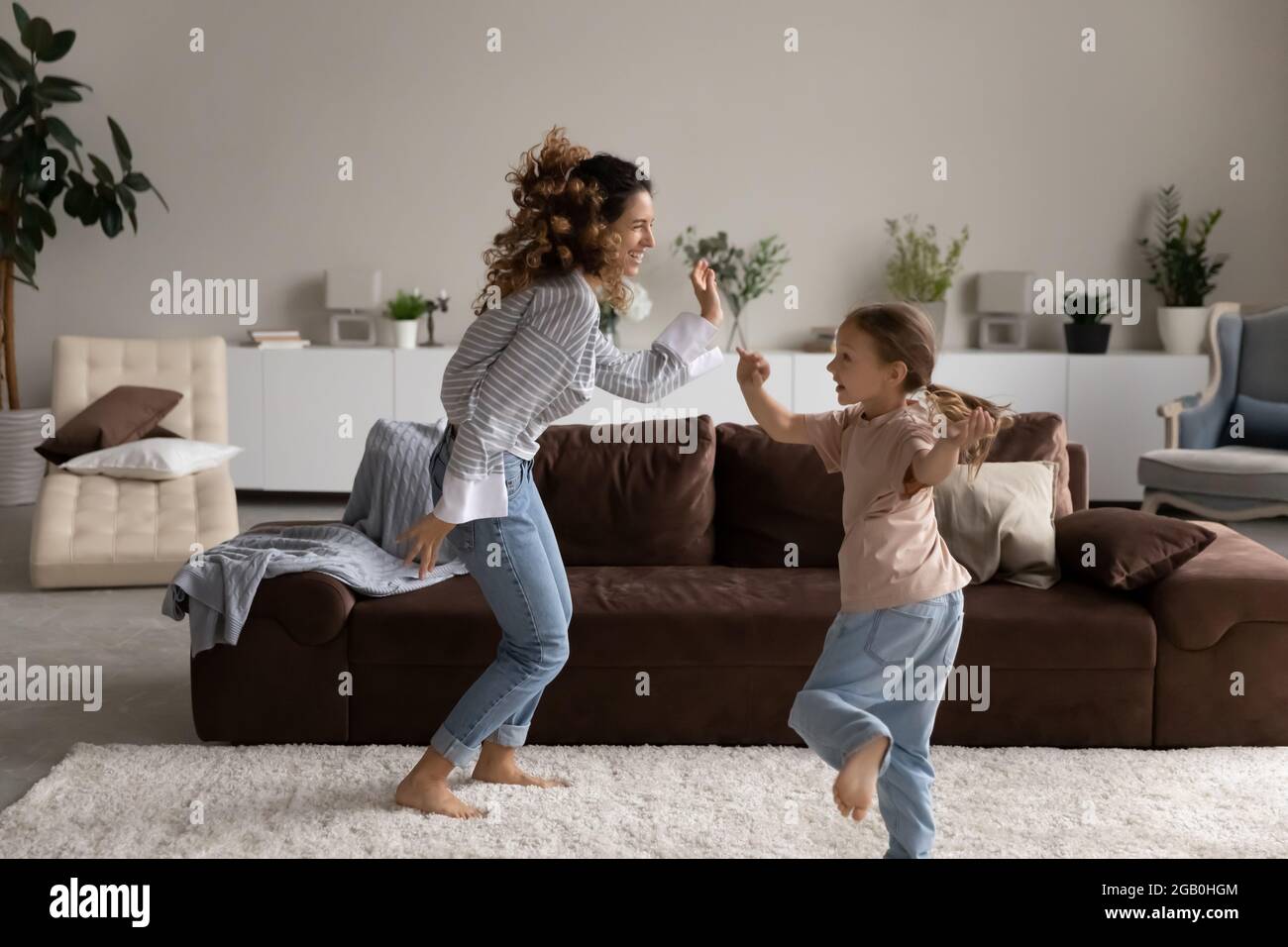 Happy excited young mom and little girl dancing to music Stock Photo ...