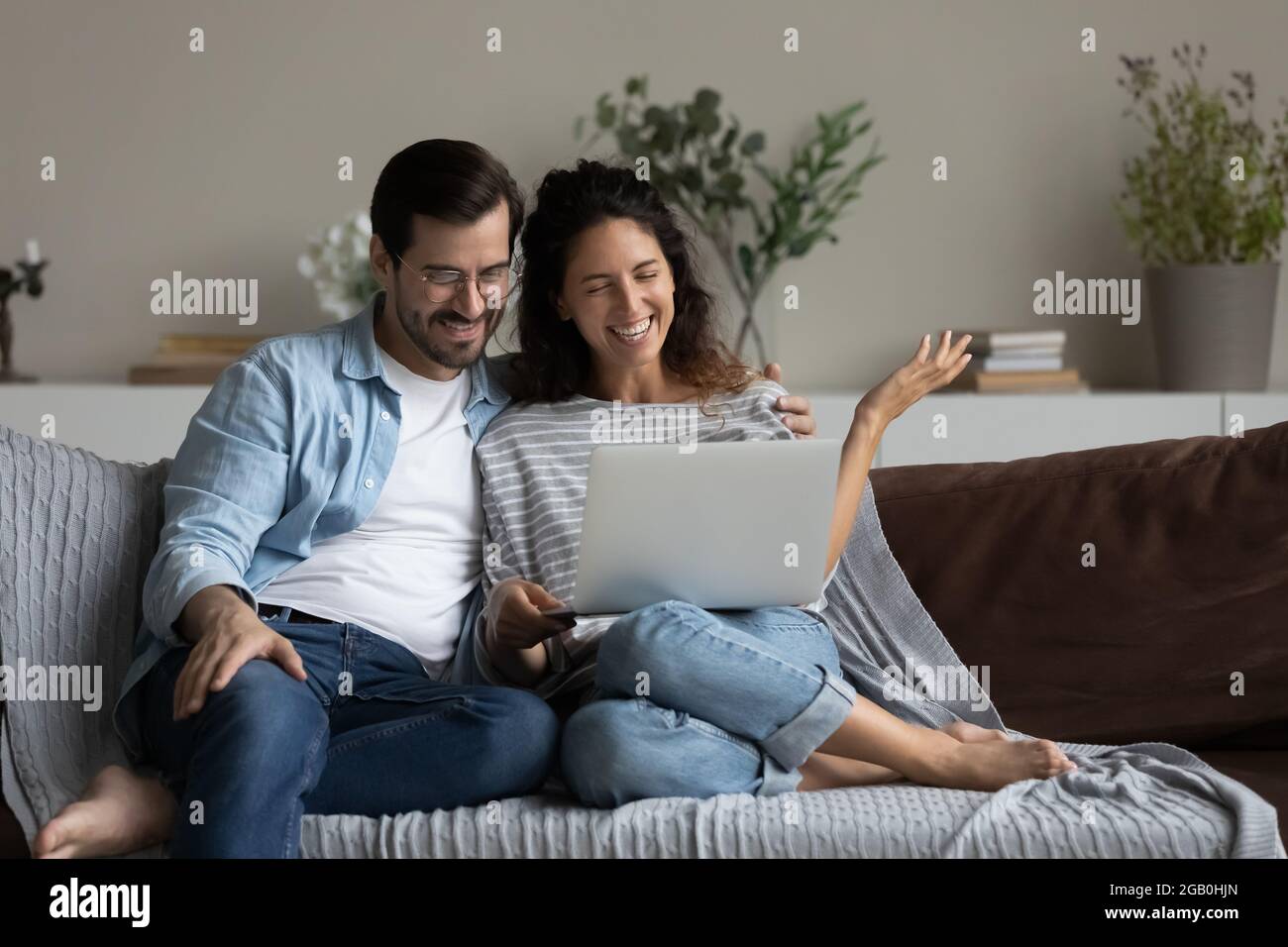 Happy millennial couple using laptop for video call from home Stock Photo