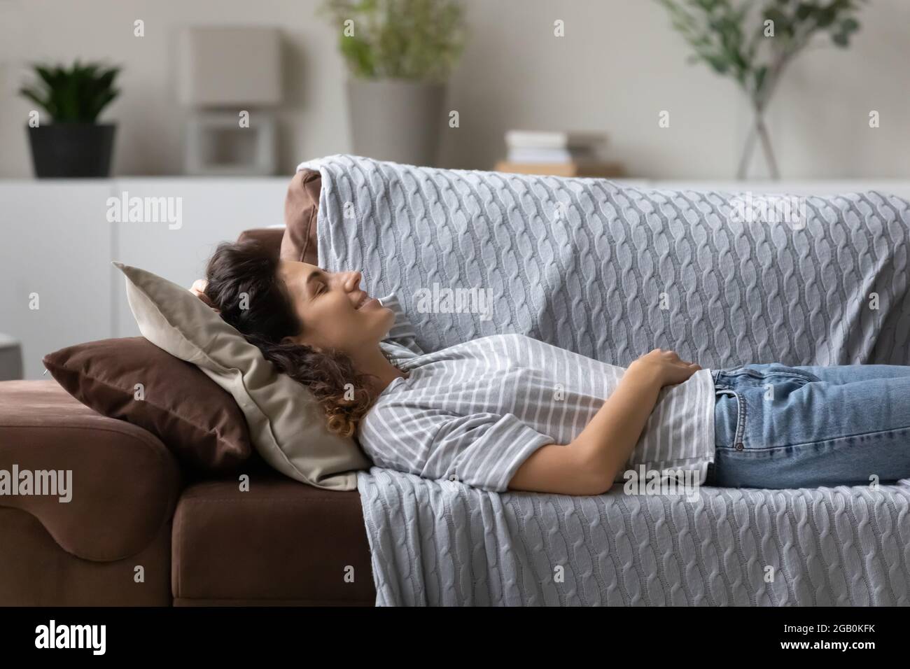 Peaceful young woman resting on cozy sofa in living room Stock Photo