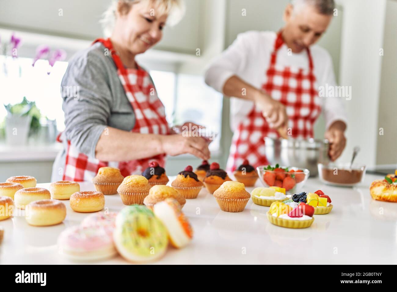 Senior caucasian couple smiling happy baking sweets at the kitchen ...