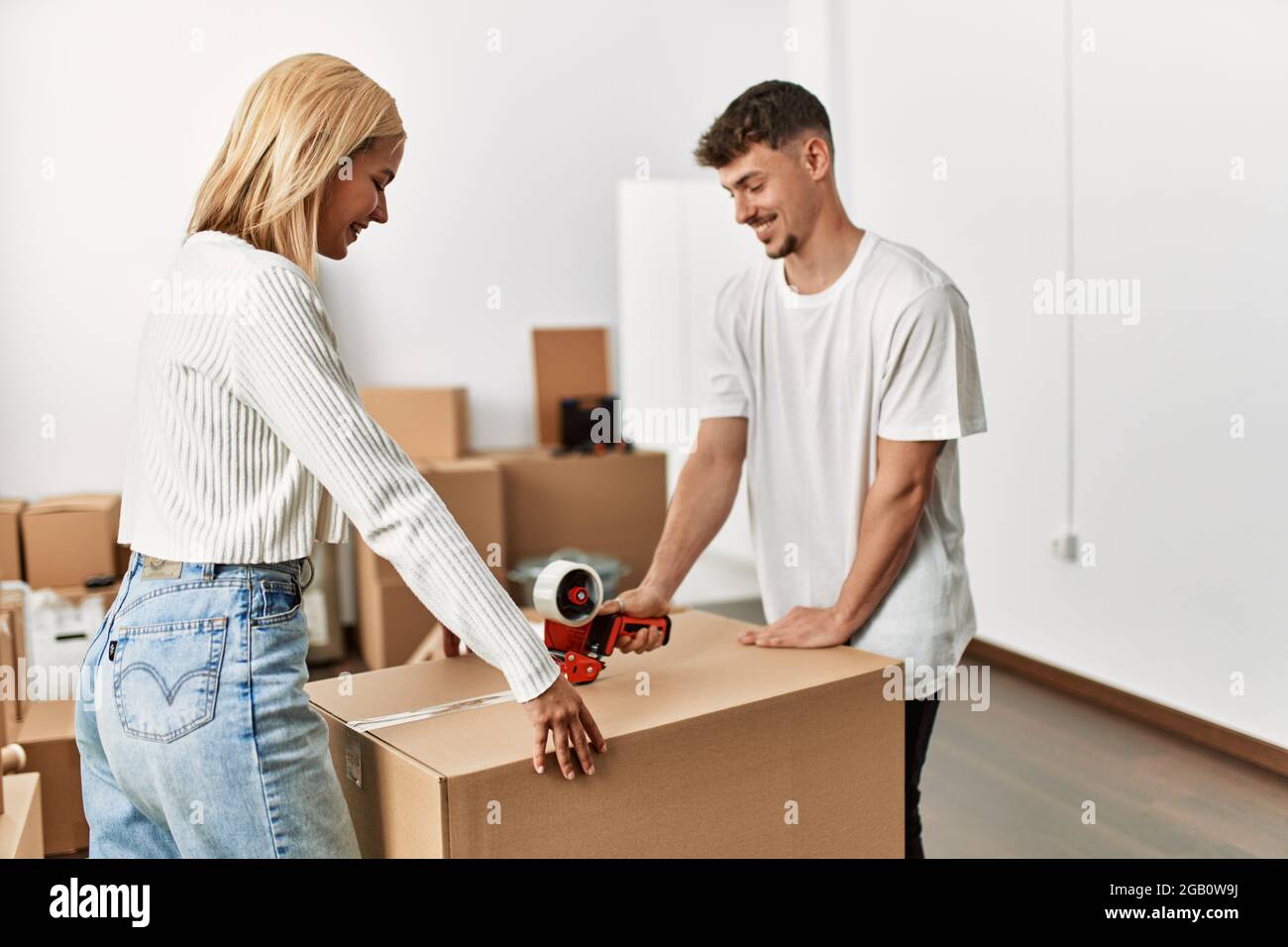 Young caucasian couple smiling happy closing box using packing tape at ...