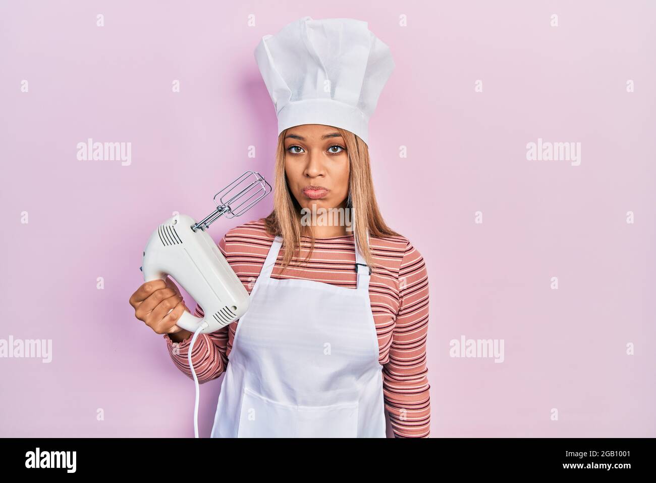 Beautiful hispanic woman holding pastry blender electric mixer ...