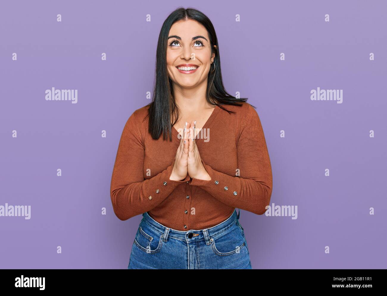 Young hispanic woman wearing casual clothes begging and praying with ...