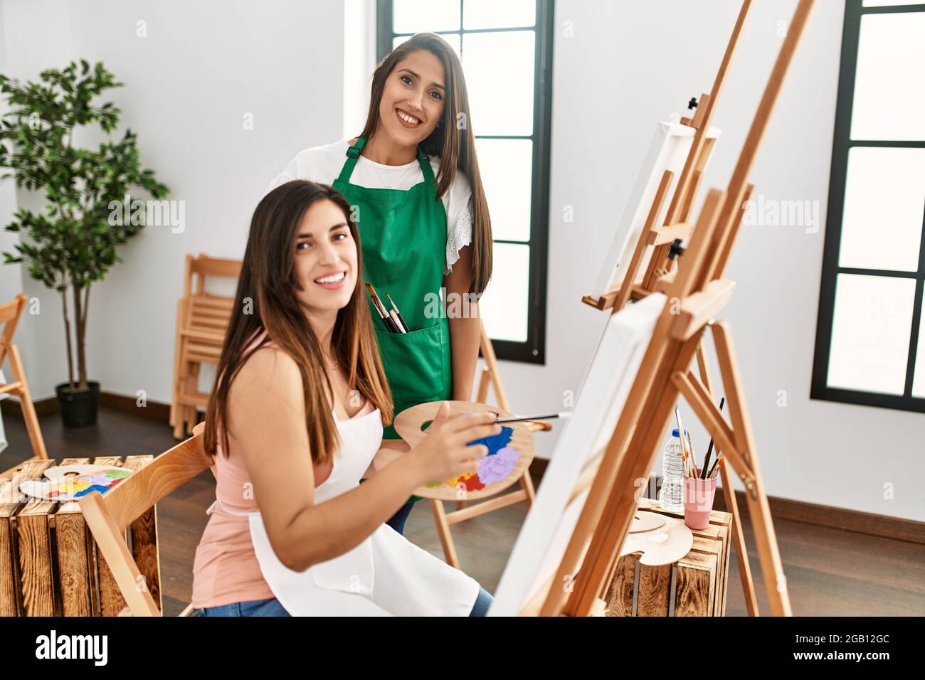Student and teacher smiling happy painting at art school Stock Photo ...