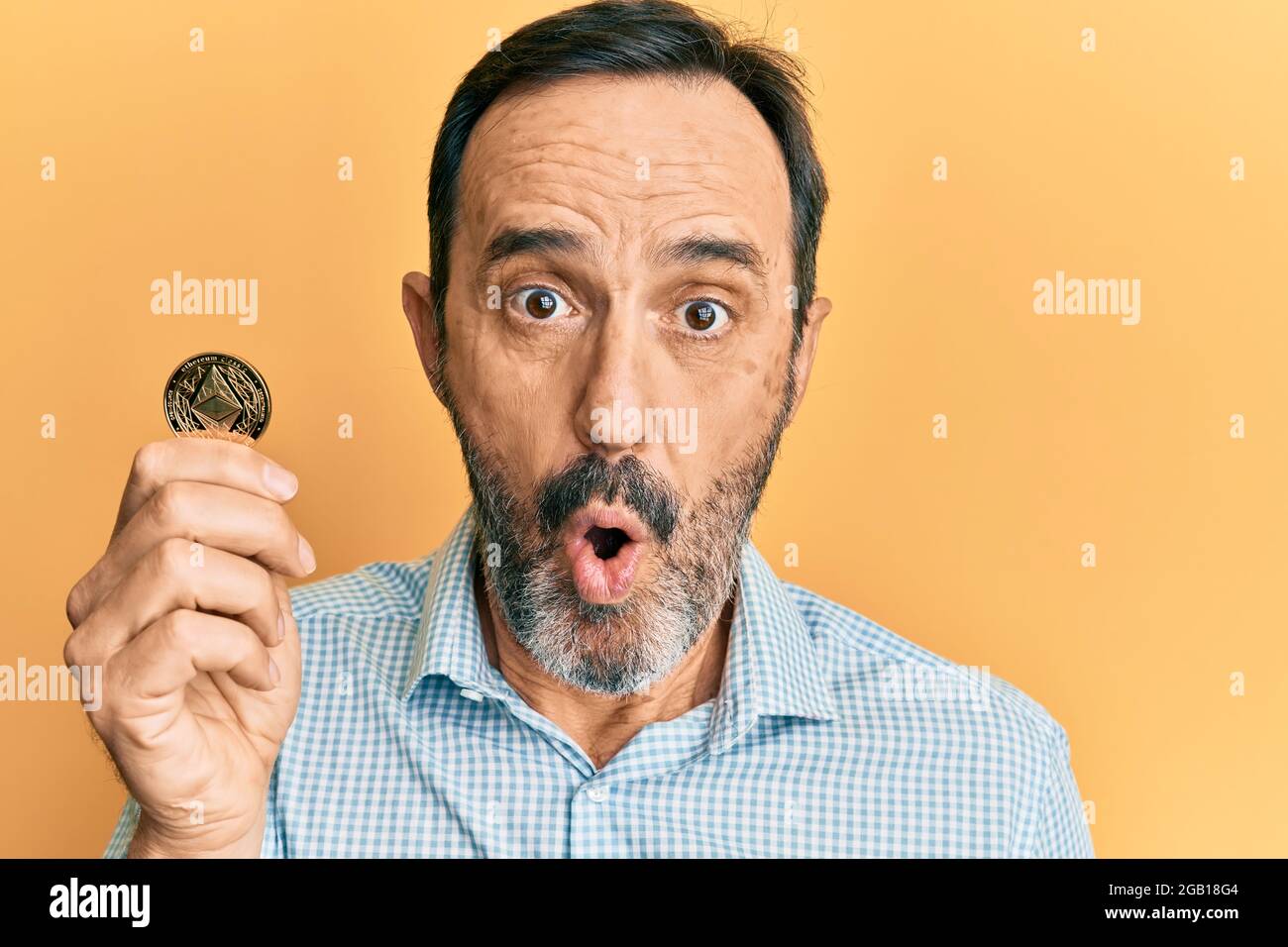 Coiny Scared Middle age hispanic man holding virtual currency ethereum coin scared ...
