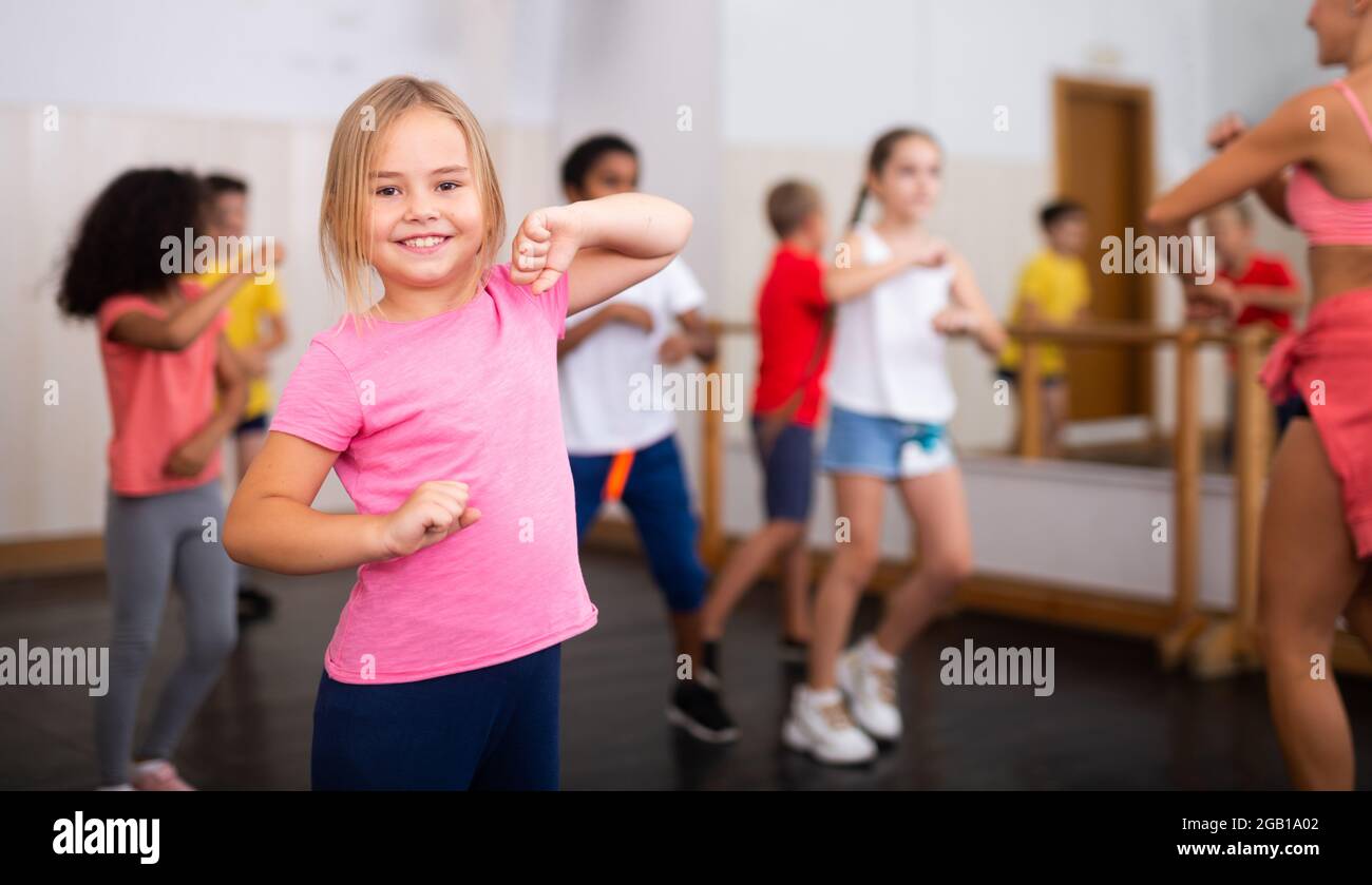 Smiling little girl training movements in children dance studio Stock