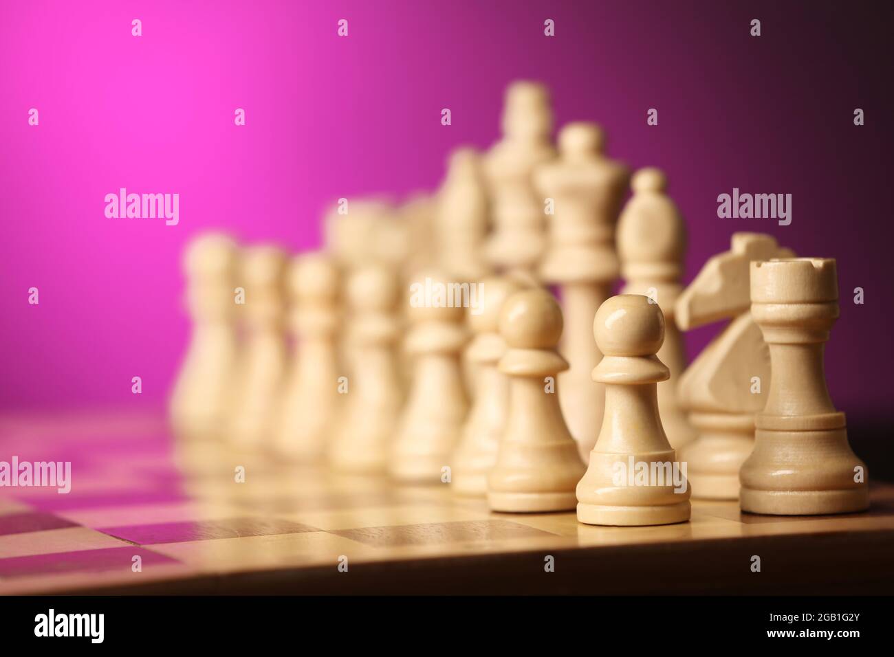 Chess pieces and game board on purple blurred background Stock Photo