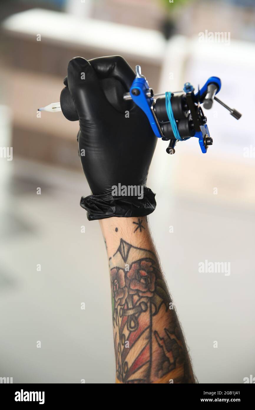 Hand of a tattoo artist holding the tattoo gun Tattooers hand and a tattoo  machine  CanStock