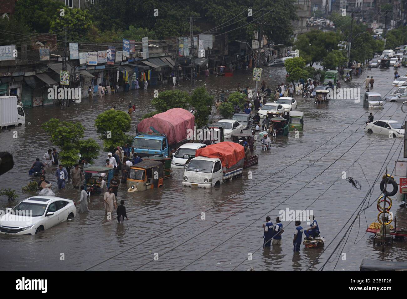 Pakistani commuters wade through a flooded road after heavy monsoon ...