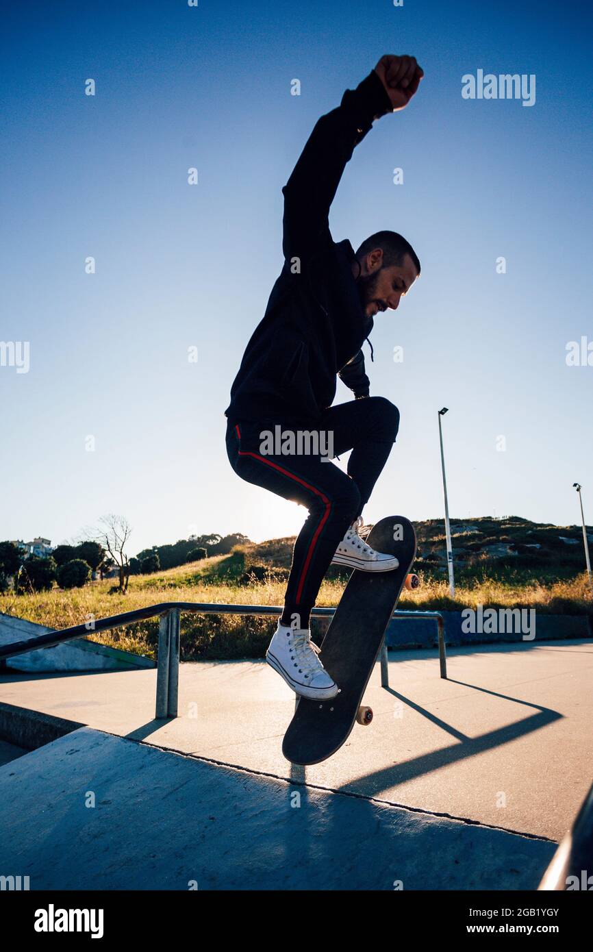 Skateboarder makes jump trick on board against sunset Stock Photo